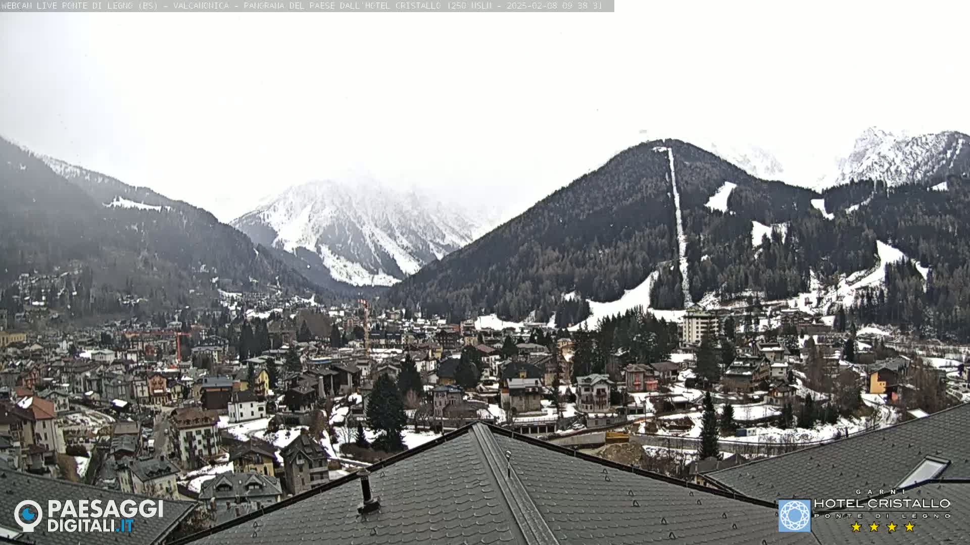 A snow-covered mountain town nestled in a valley between snow-capped mountains under an overcast sky.