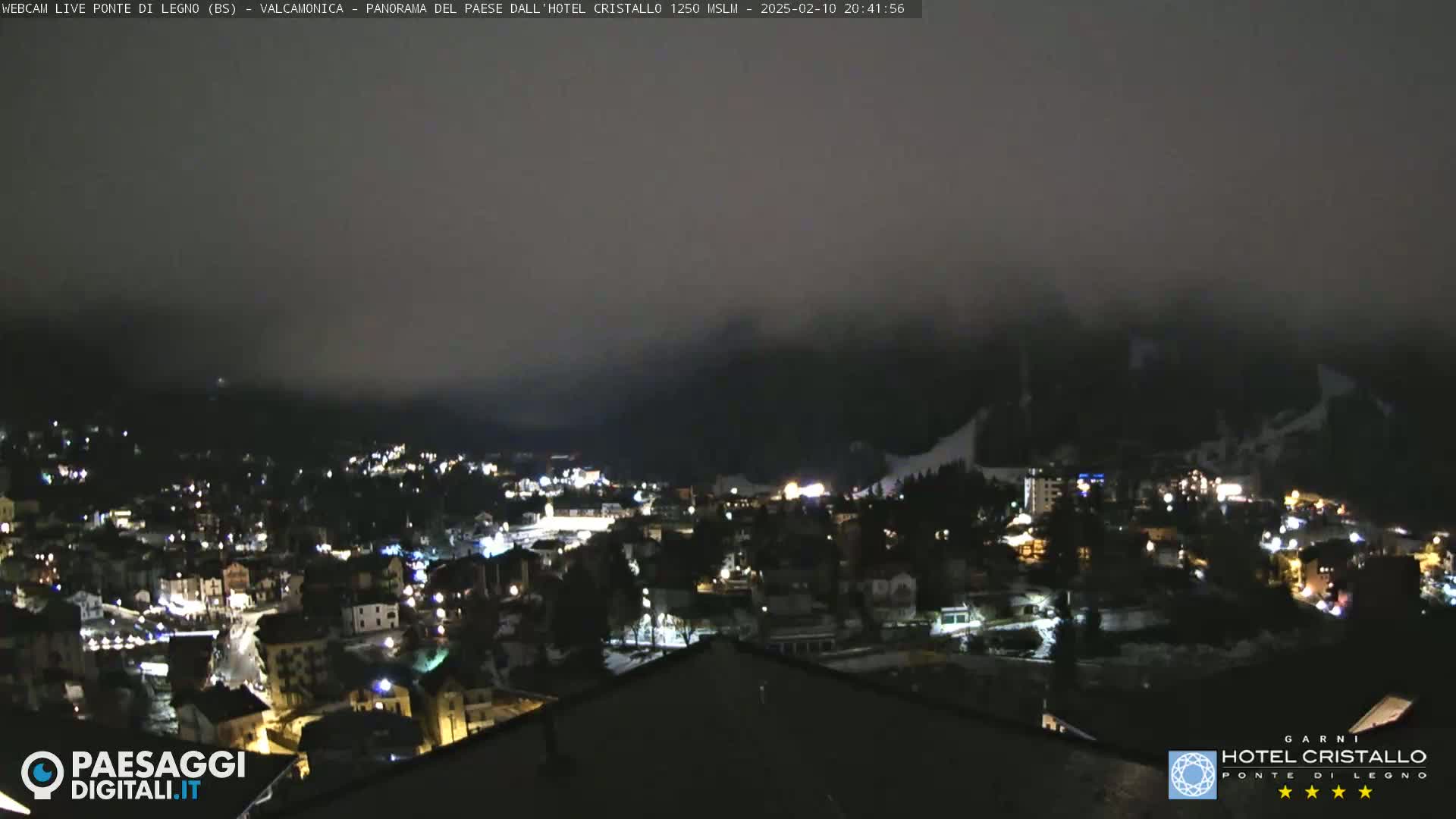 A nighttime view of a snow-covered mountain town under a foggy sky.