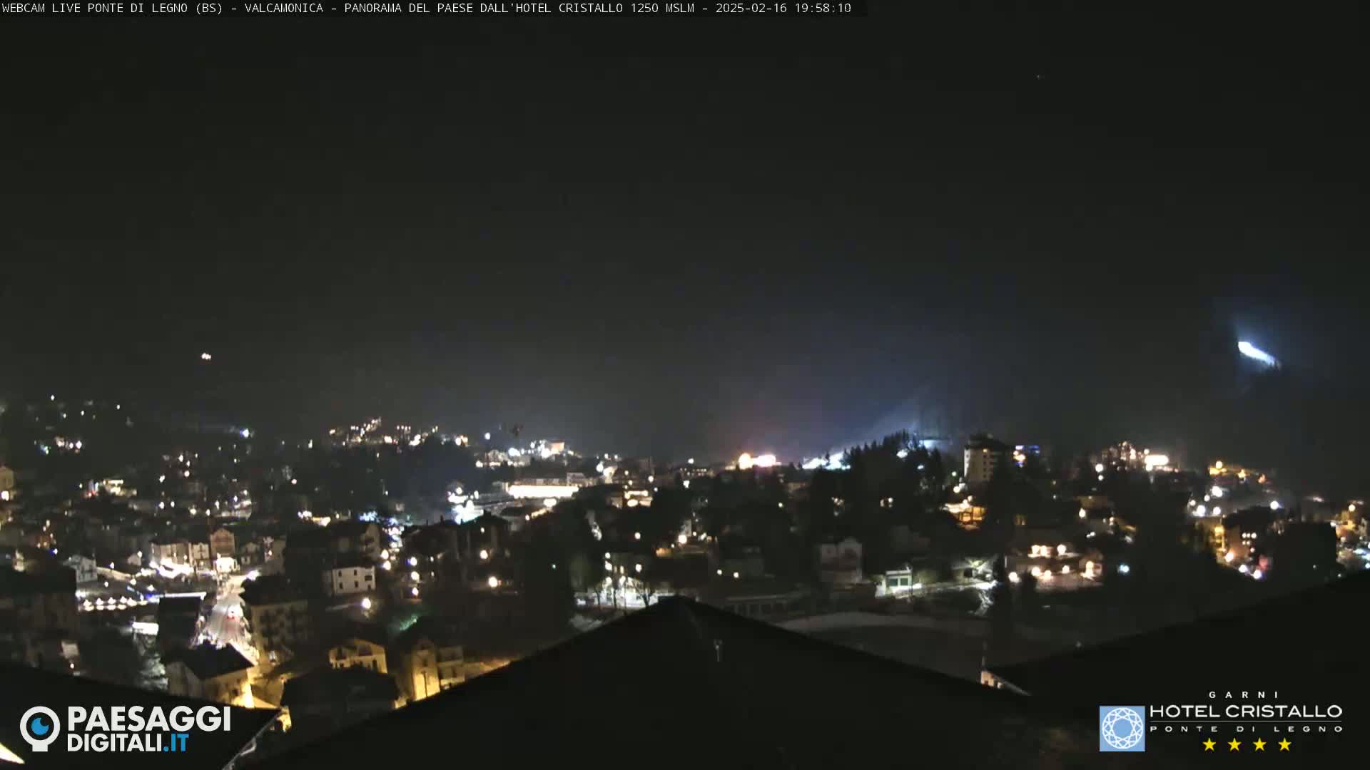 A nighttime long shot of a town illuminated by lights under a clear, dark sky.