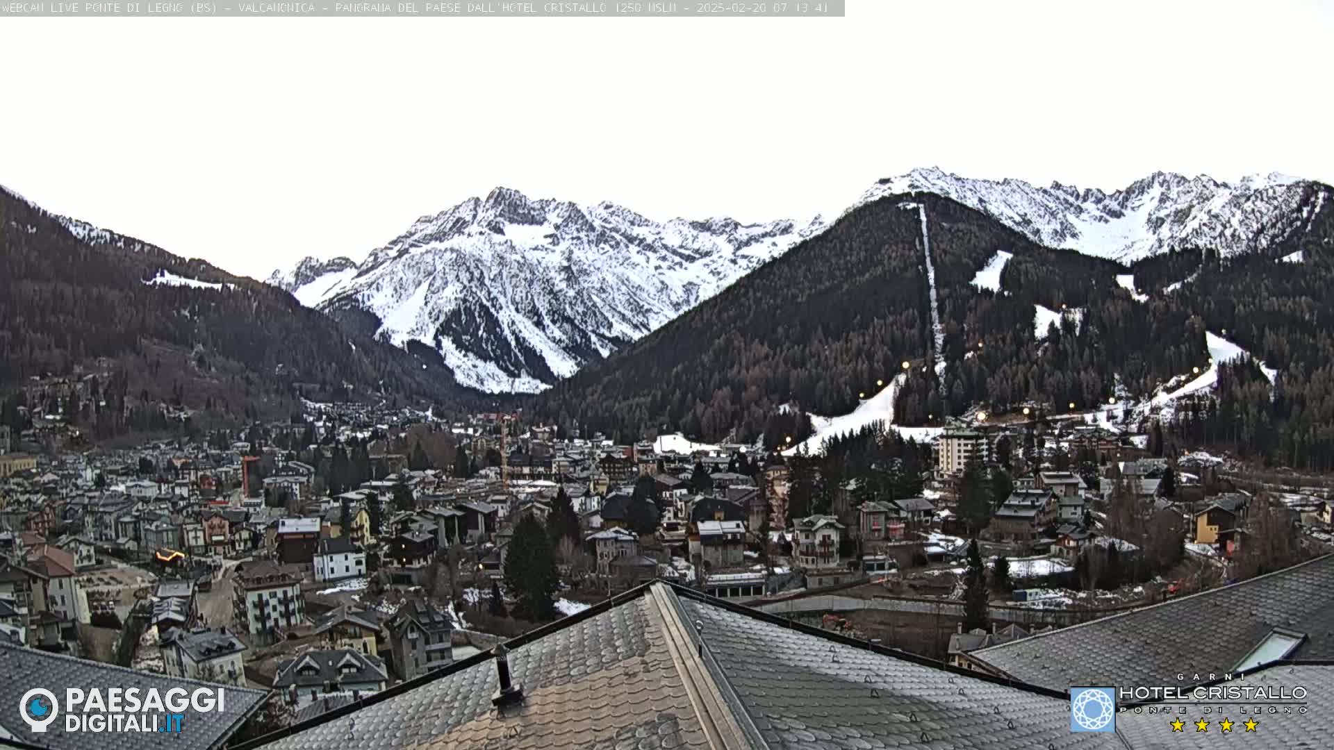 A snow-covered mountain range overlooks a town nestled in a valley.