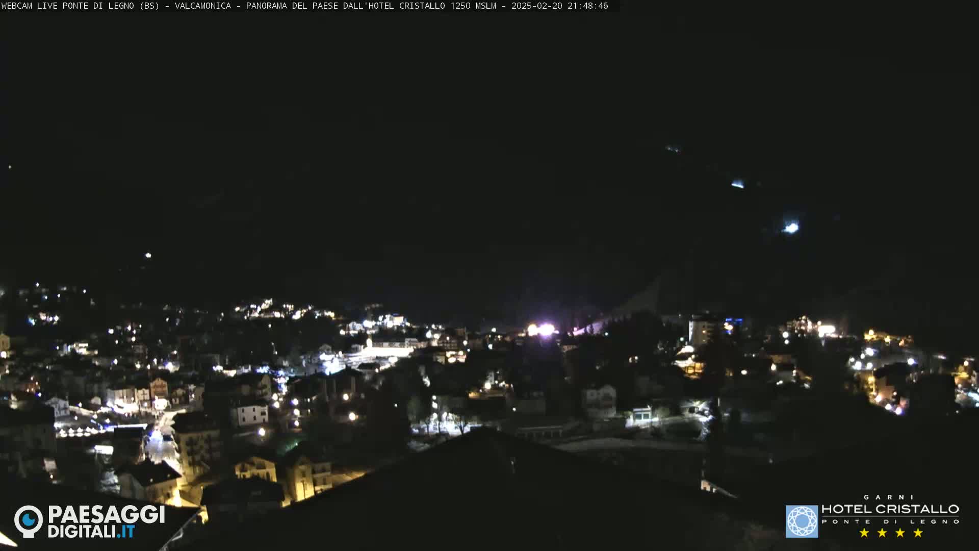 A nighttime view of a town illuminated by lights, under a clear, dark sky.
