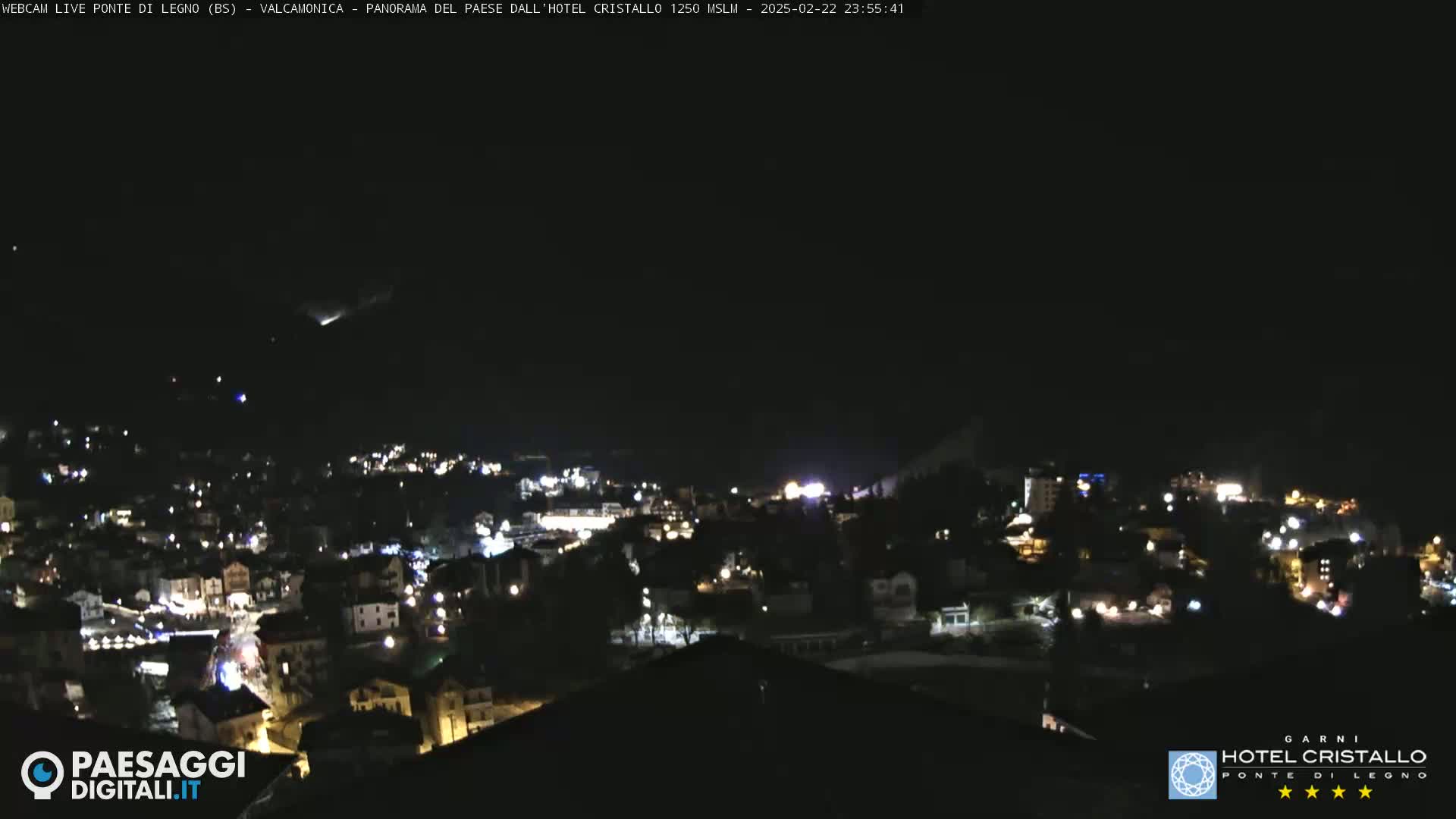 A nighttime, long shot of a town nestled in a valley under a clear, dark sky.