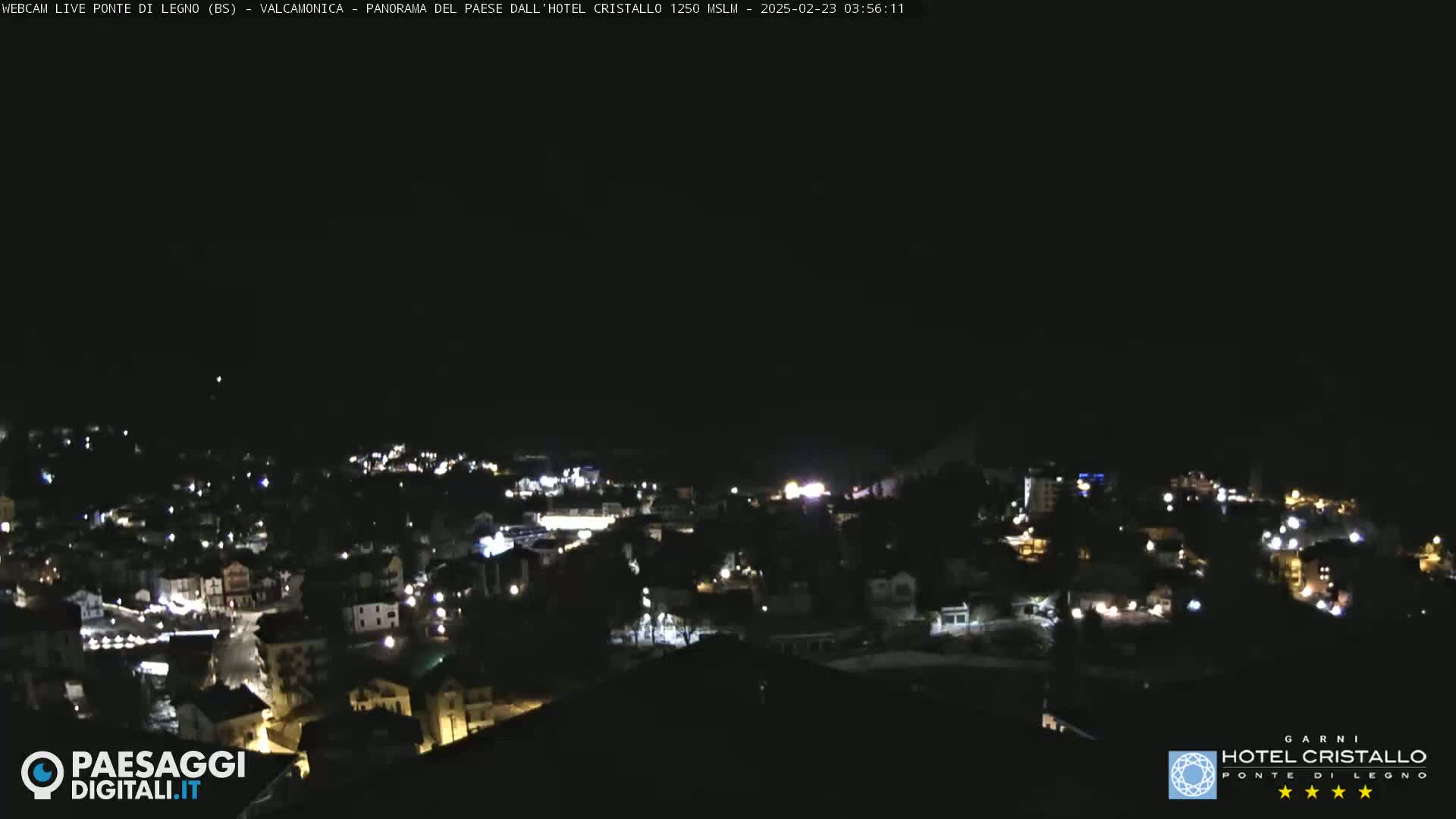 A nighttime, aerial view of a town's illuminated buildings and streets under a dark, clear sky.