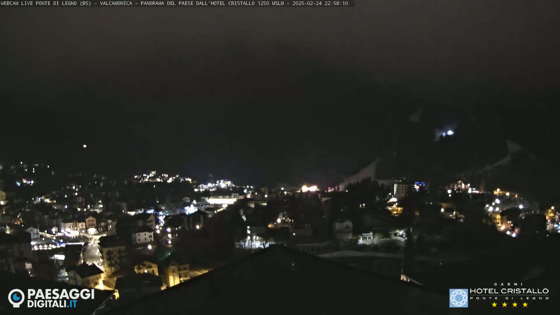 A nighttime view of a snow-covered mountainside and a town illuminated with lights.