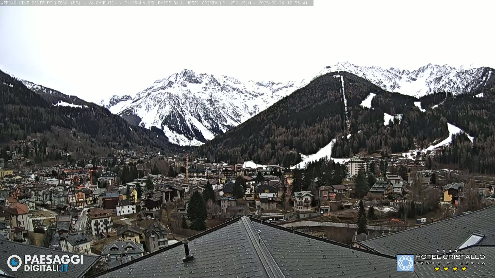 A snow-covered mountain range overlooks a town nestled in a valley.