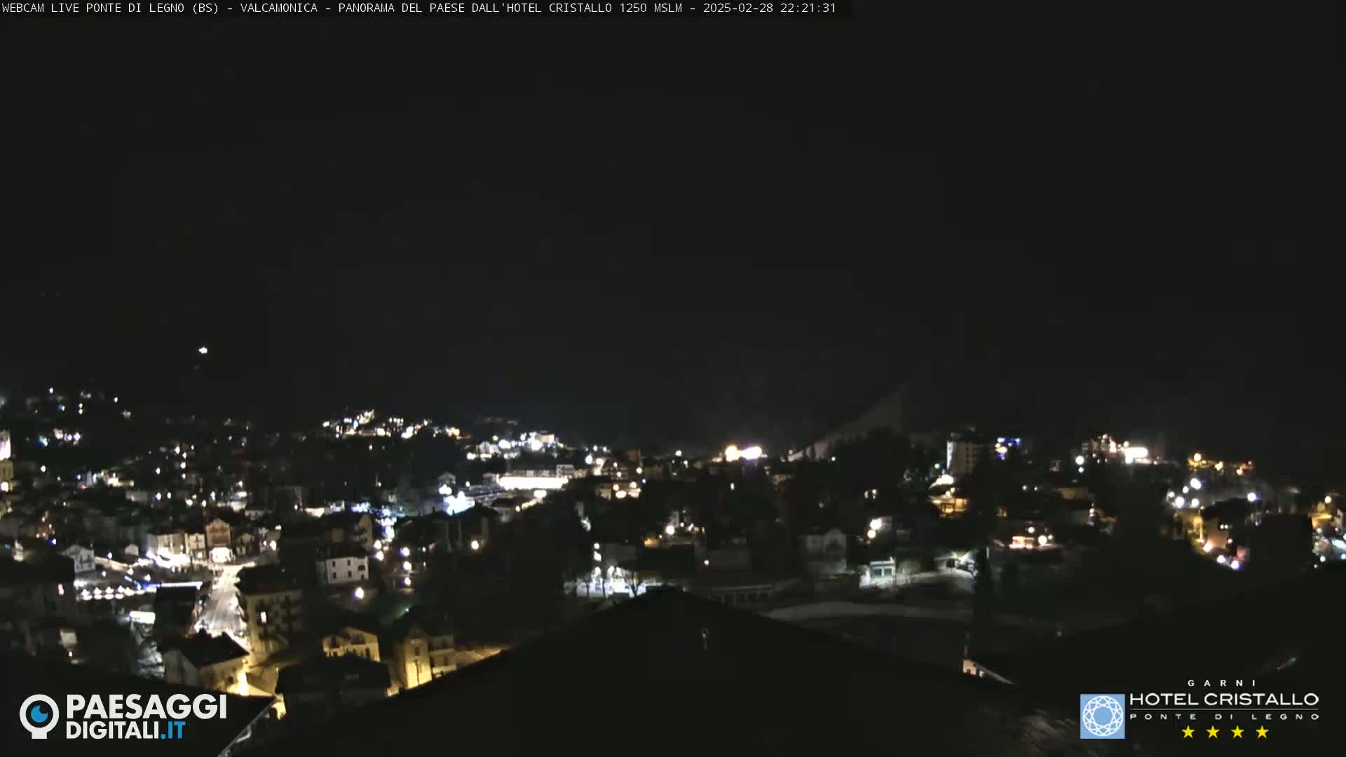 A nighttime, high-angle view of a town illuminated by scattered lights under a dark sky.