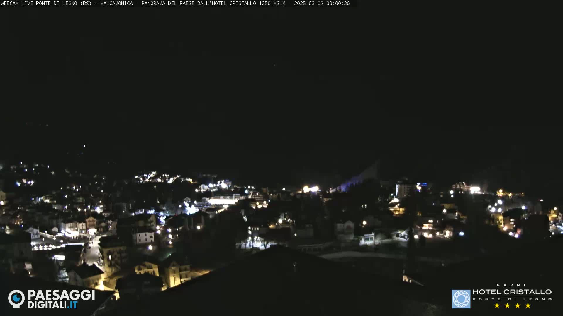 A nighttime, aerial view of a small town illuminated by streetlights under a dark sky.