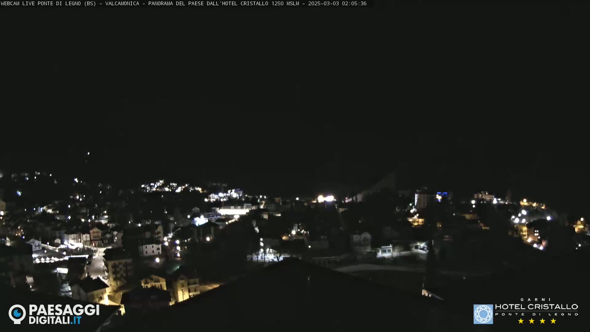 A nighttime view of a town illuminated by scattered lights under a dark sky.