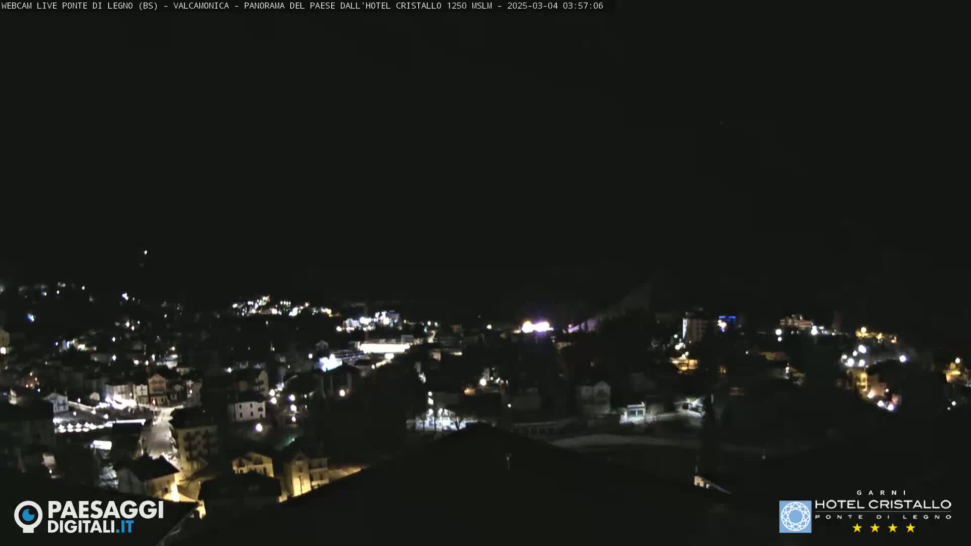 A nighttime view of a small town illuminated by scattered lights under a clear, dark sky.