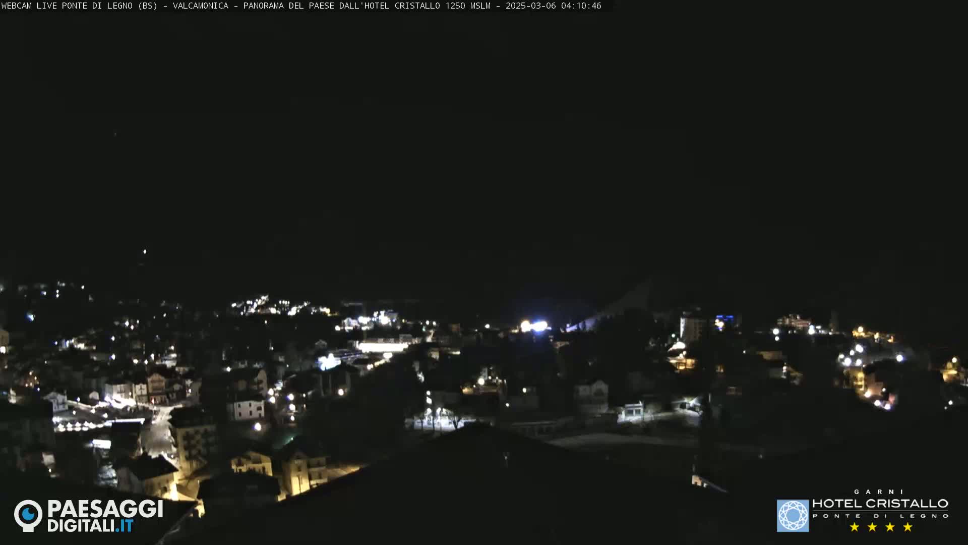 A nighttime view of a town illuminated by streetlights under a dark, clear sky.
