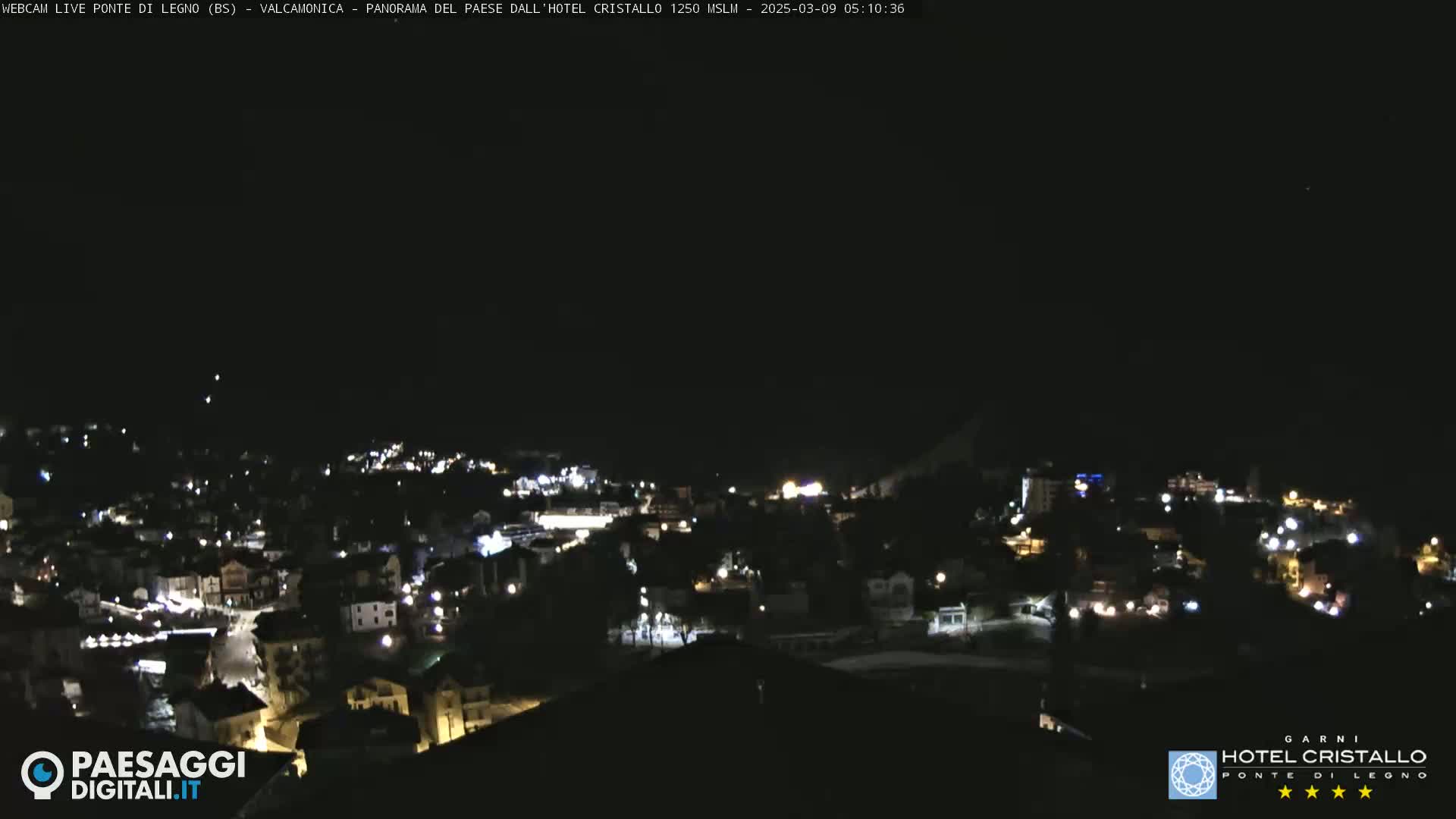 A nighttime, high-angle view of a town illuminated by lights under a clear, dark sky.