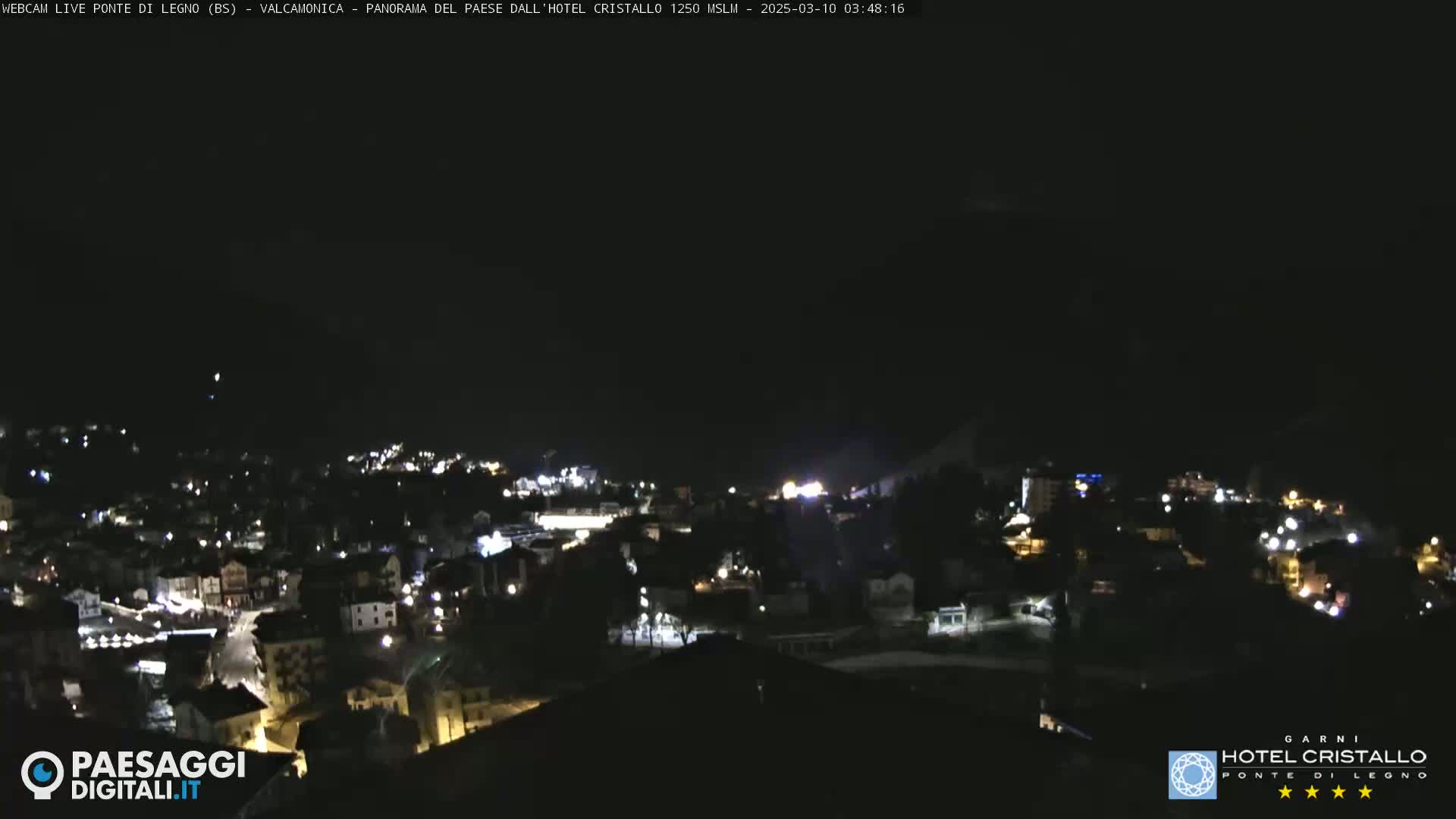 A nighttime, high-angle view of a town nestled in a valley, illuminated by scattered lights.