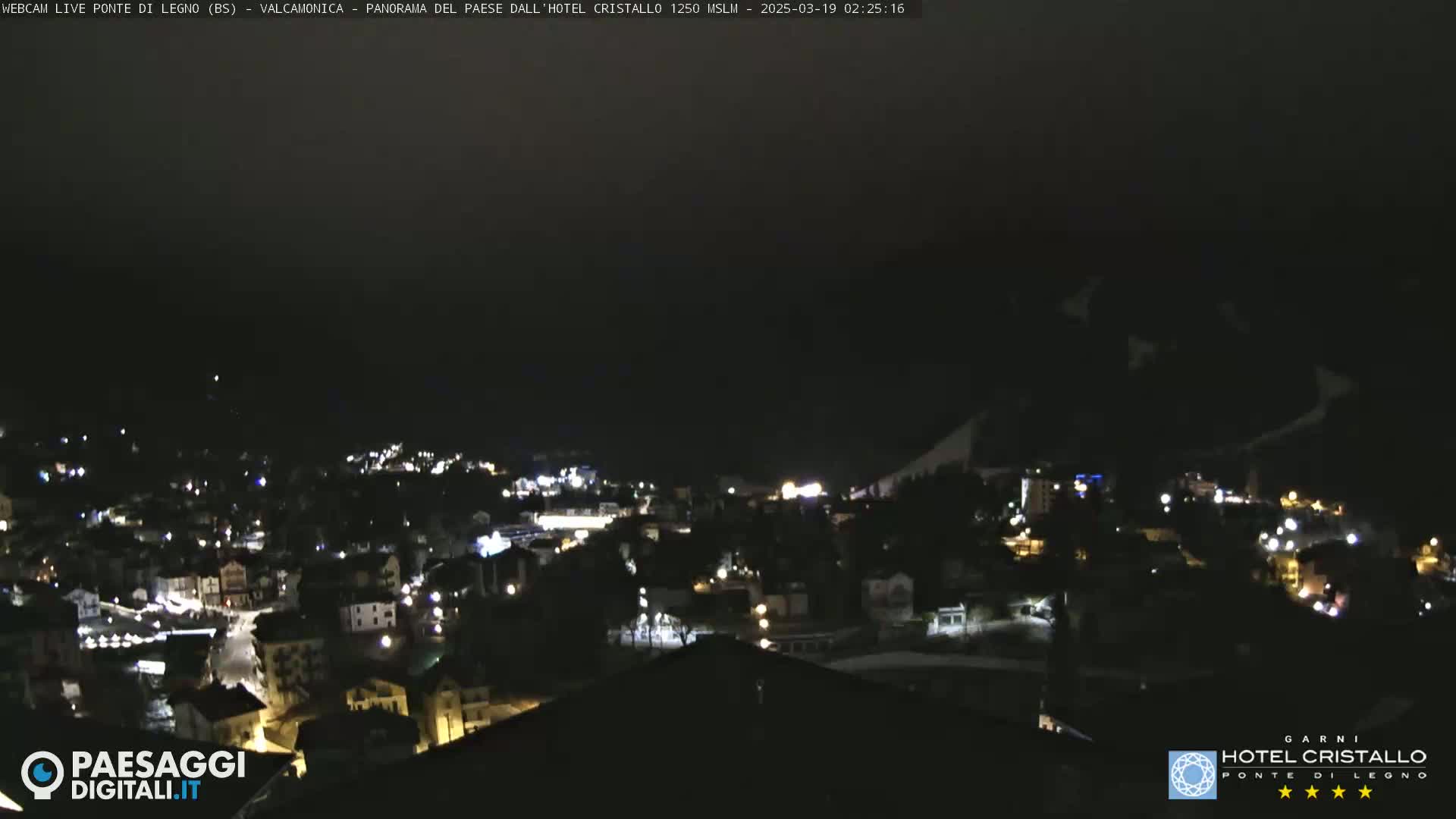 A nighttime view of a town nestled in a valley, under a dark sky.