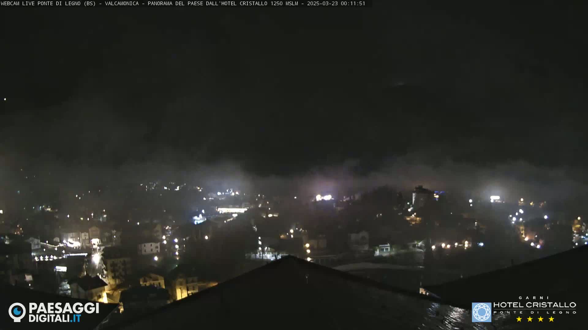 A nighttime, foggy view of a town with scattered lights.