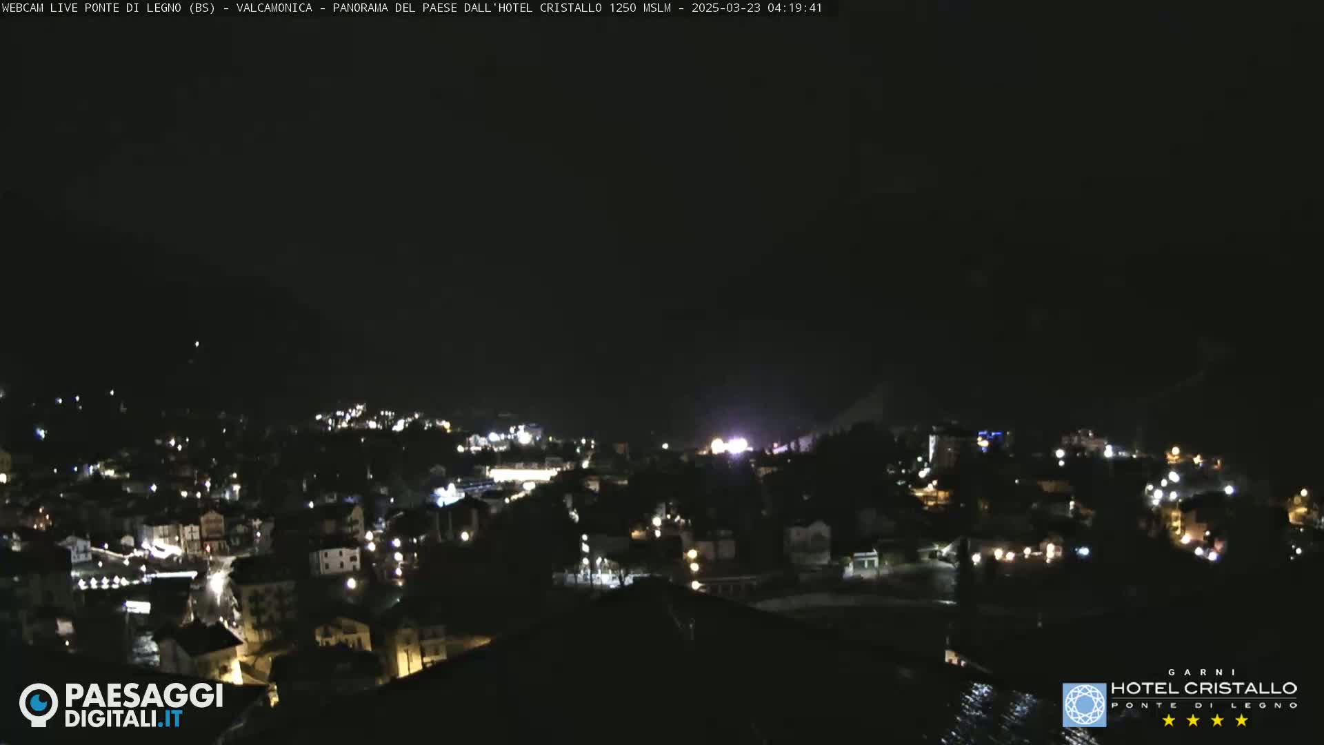 A nighttime, high-angle view of a town illuminated by scattered lights under a dark sky.