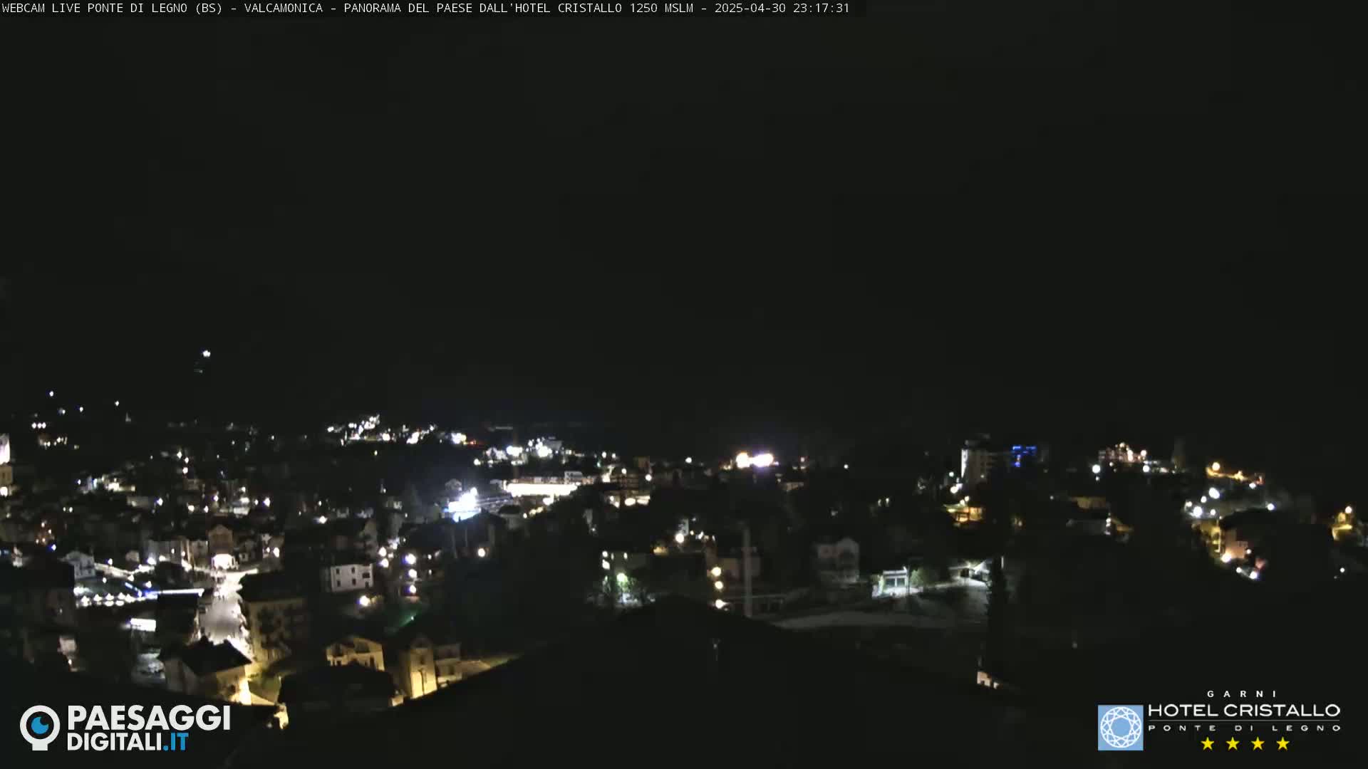 A nighttime, high-angle view of a town with scattered lights, under a dark sky.