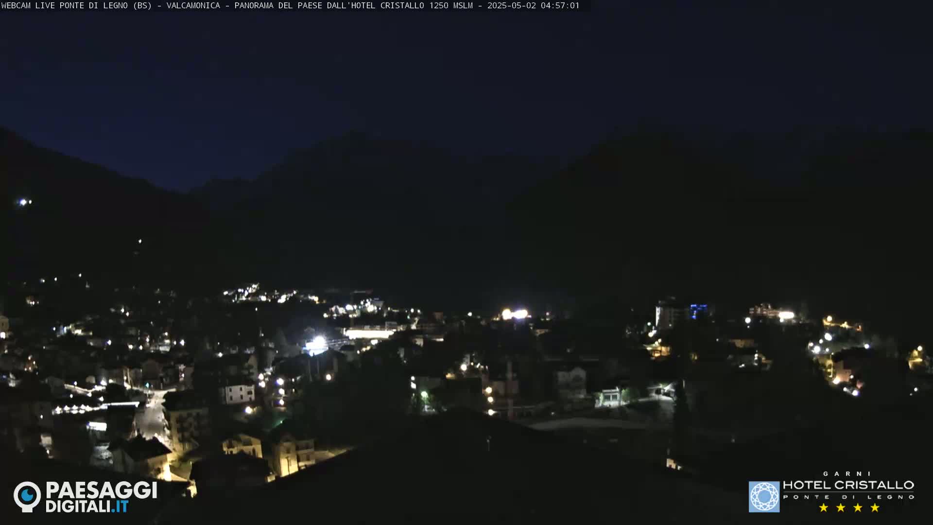 A nighttime view of a town nestled in a valley between dark mountains.