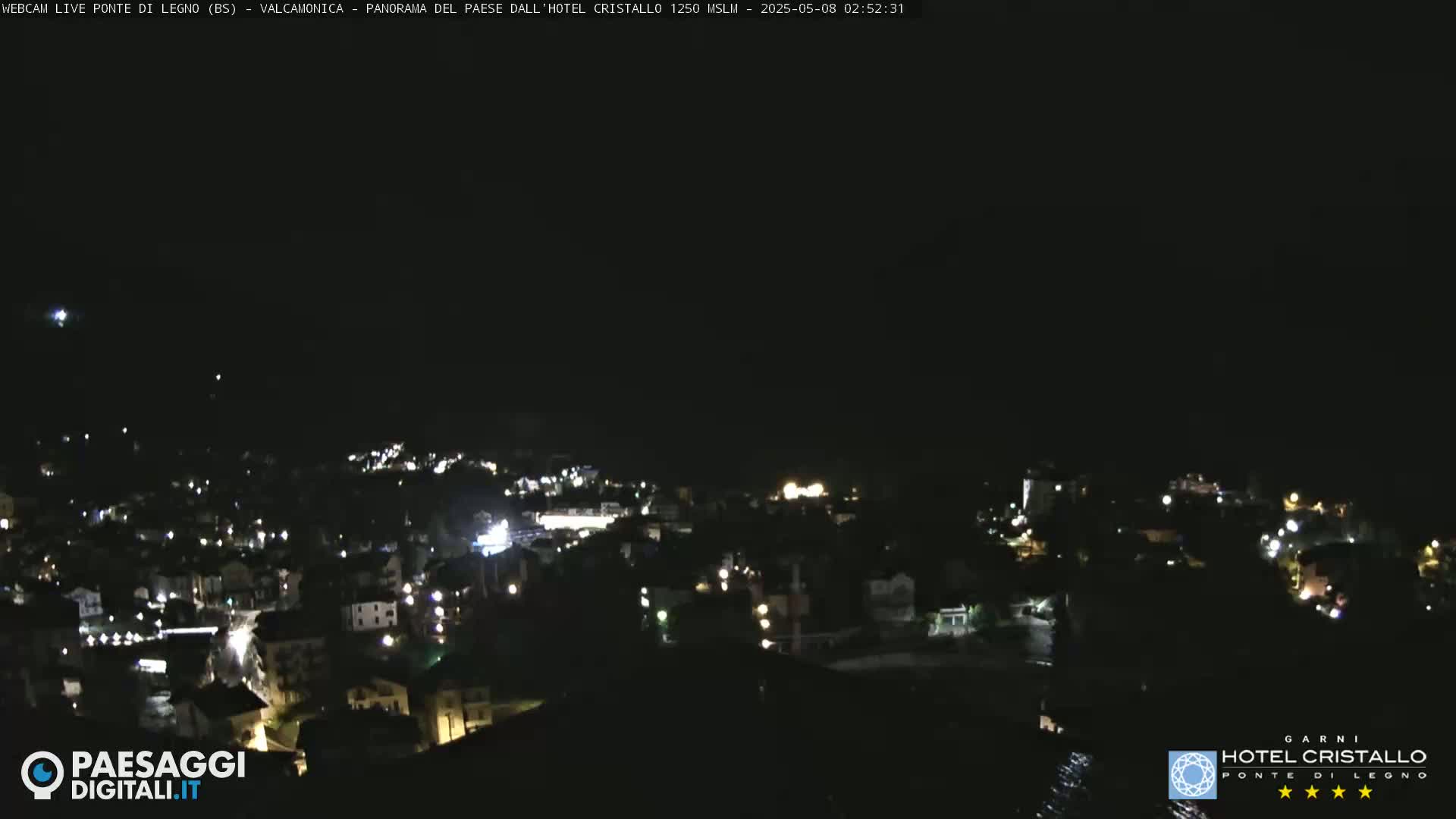 A nighttime view of a town illuminated by scattered lights under a clear, dark sky.