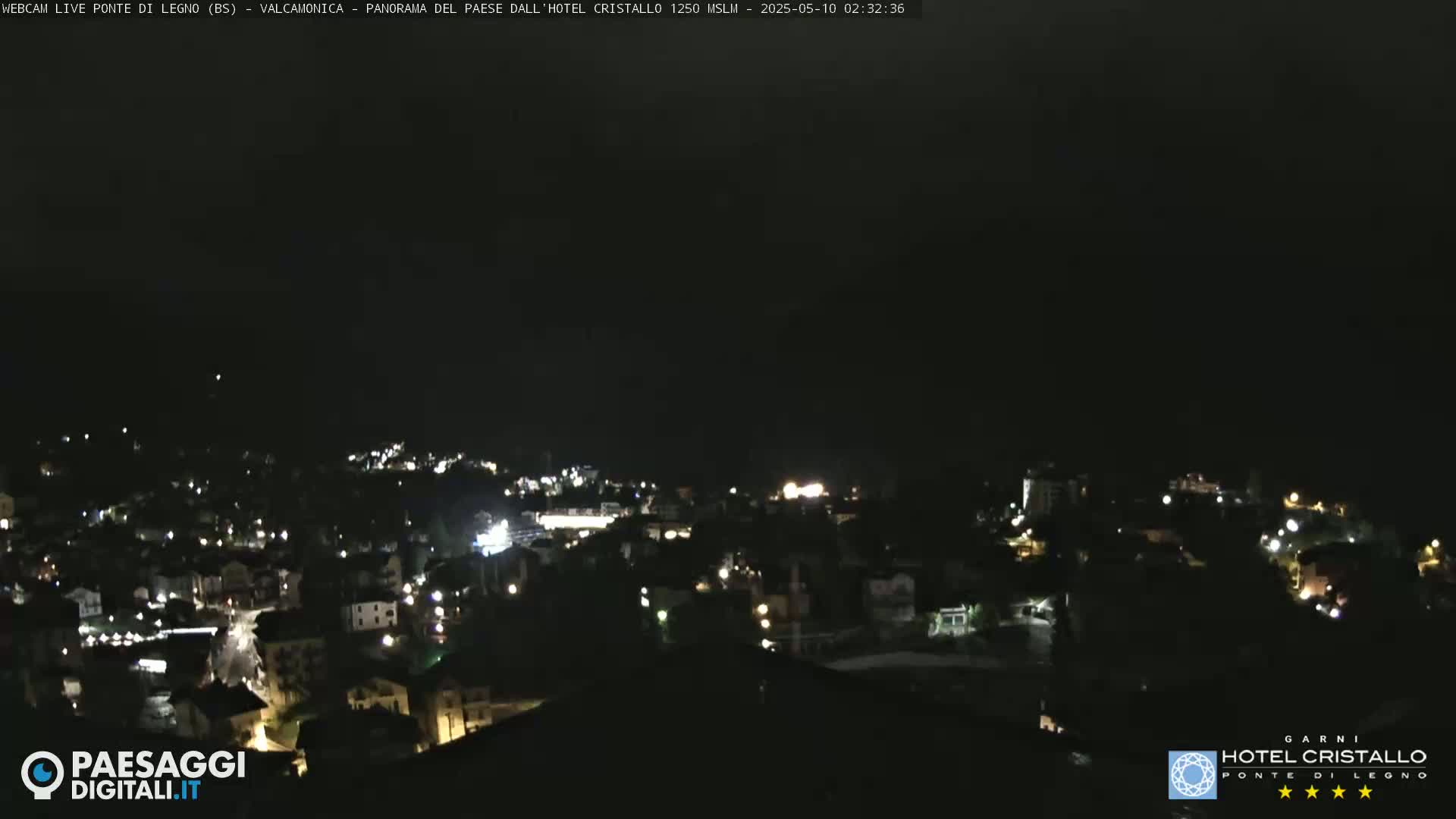 A nighttime view of a town illuminated by scattered lights under a dark, clear sky.