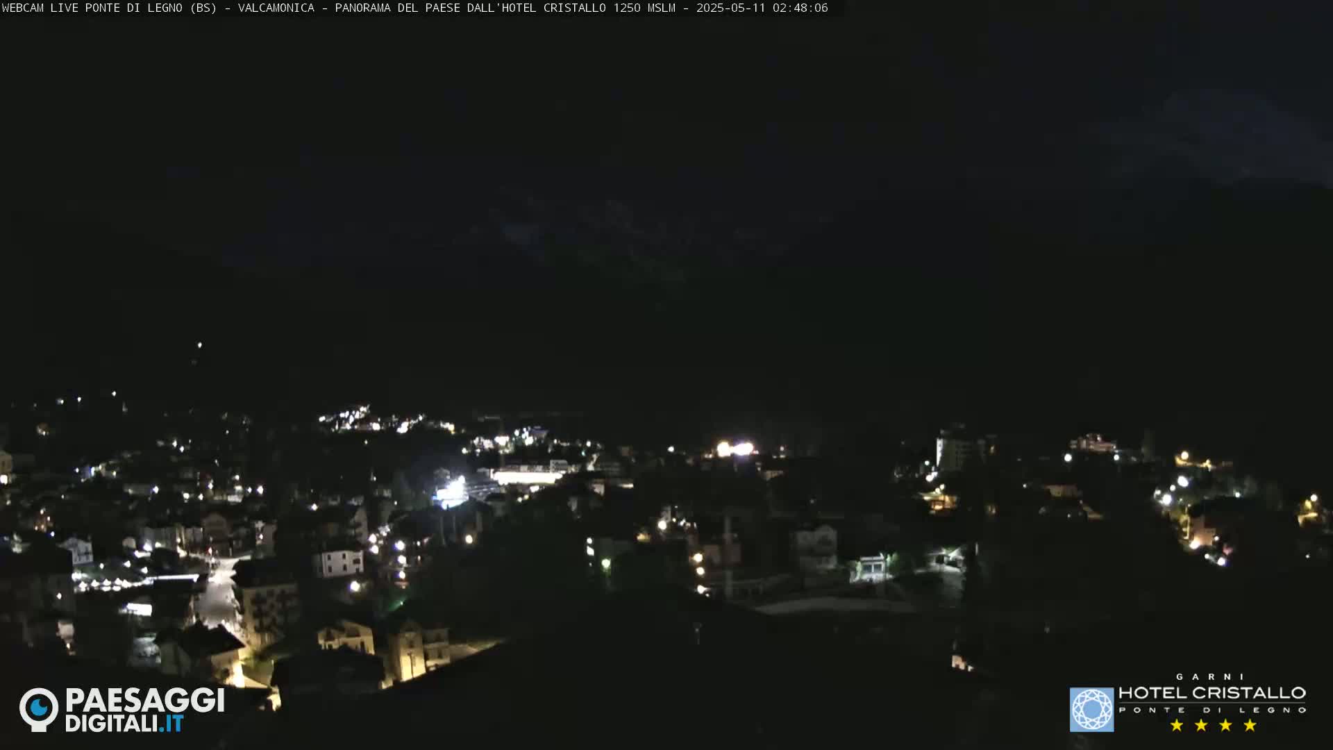 A nighttime, high-angle view of a town illuminated by scattered lights against a dark sky.
