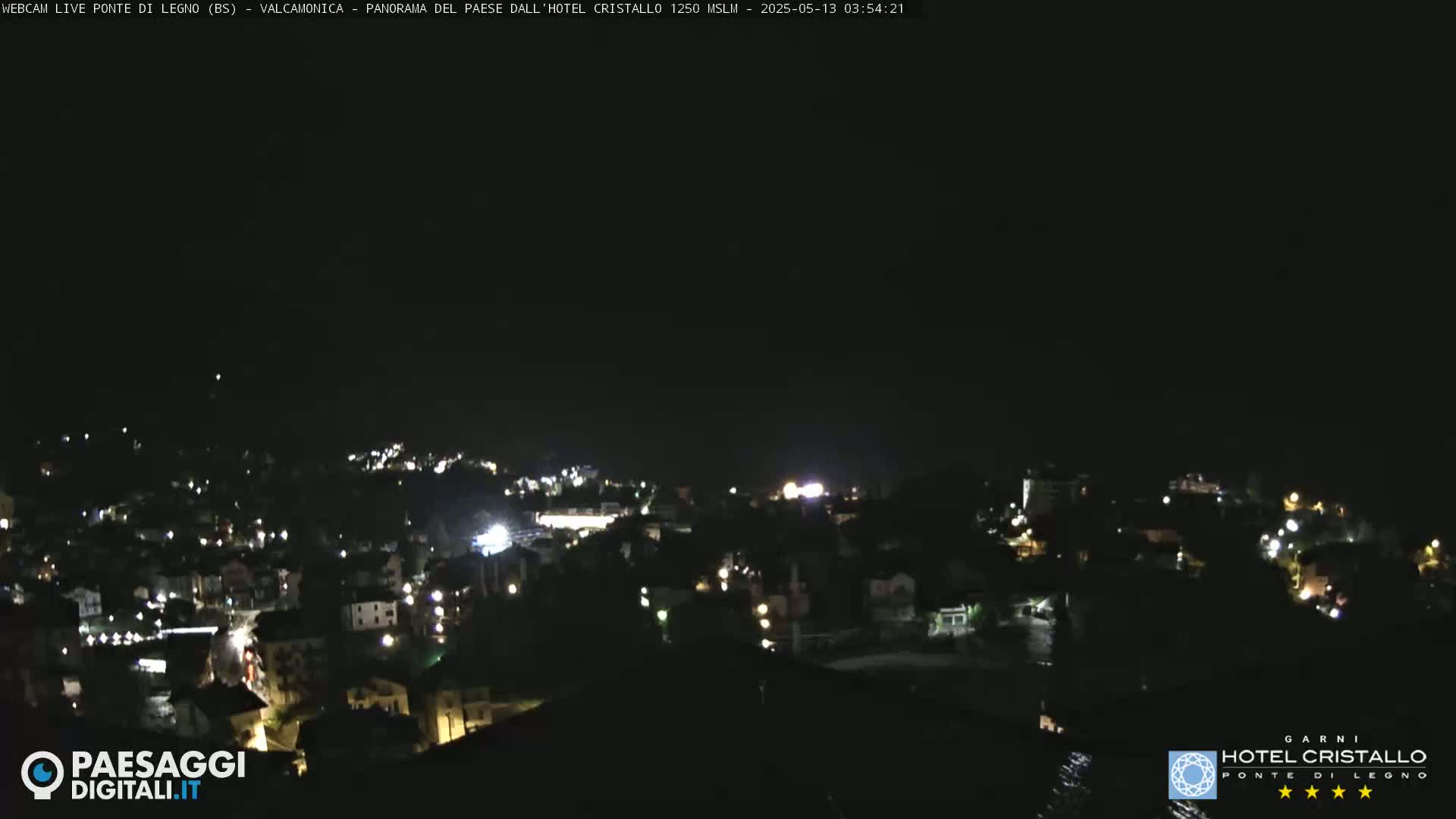 A nighttime view of a town illuminated by scattered lights under a clear, dark sky.