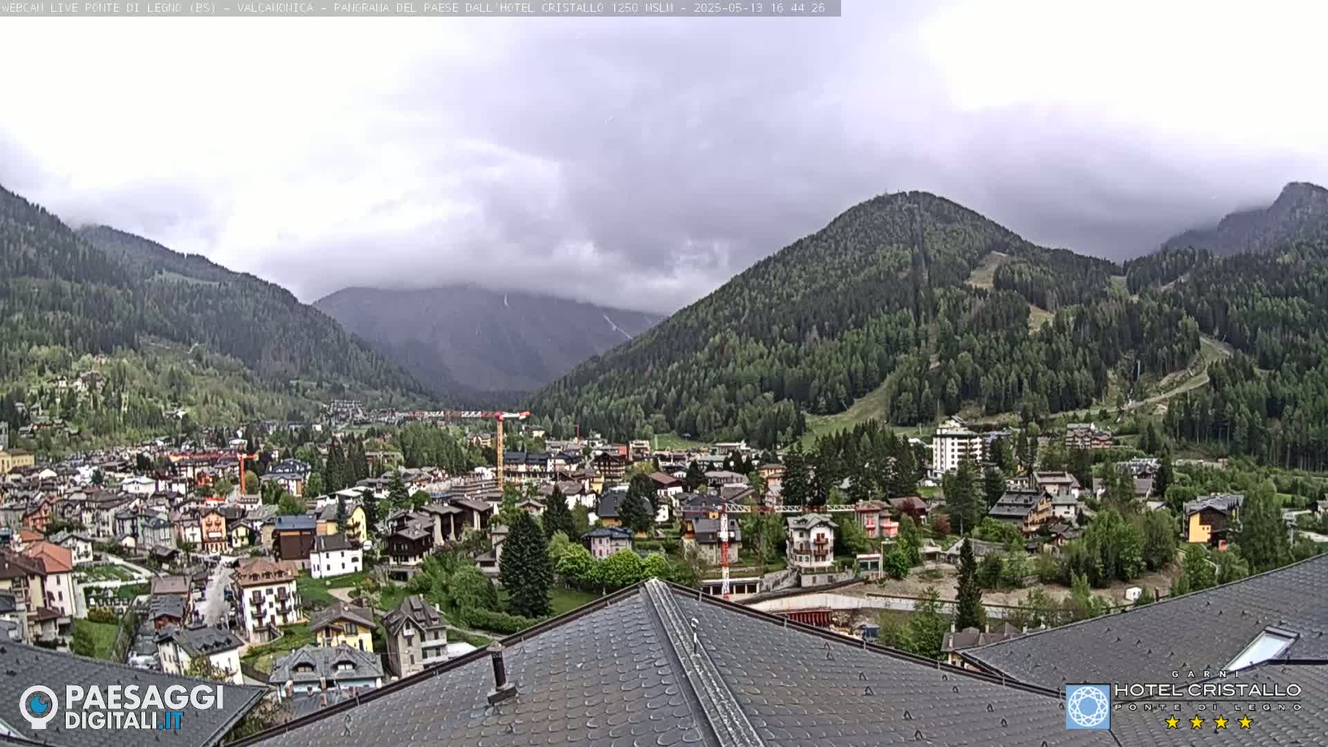 A mountain town nestled in a valley between green hills under an overcast sky.