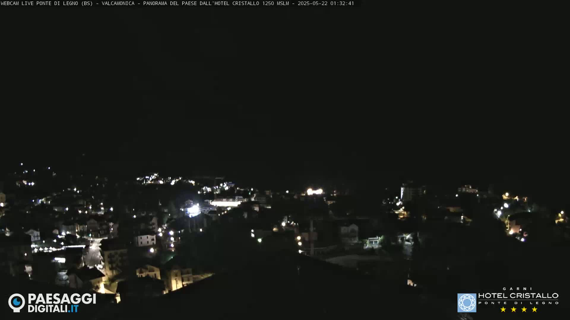A nighttime, high-angle view of a town with scattered lights under a dark sky.