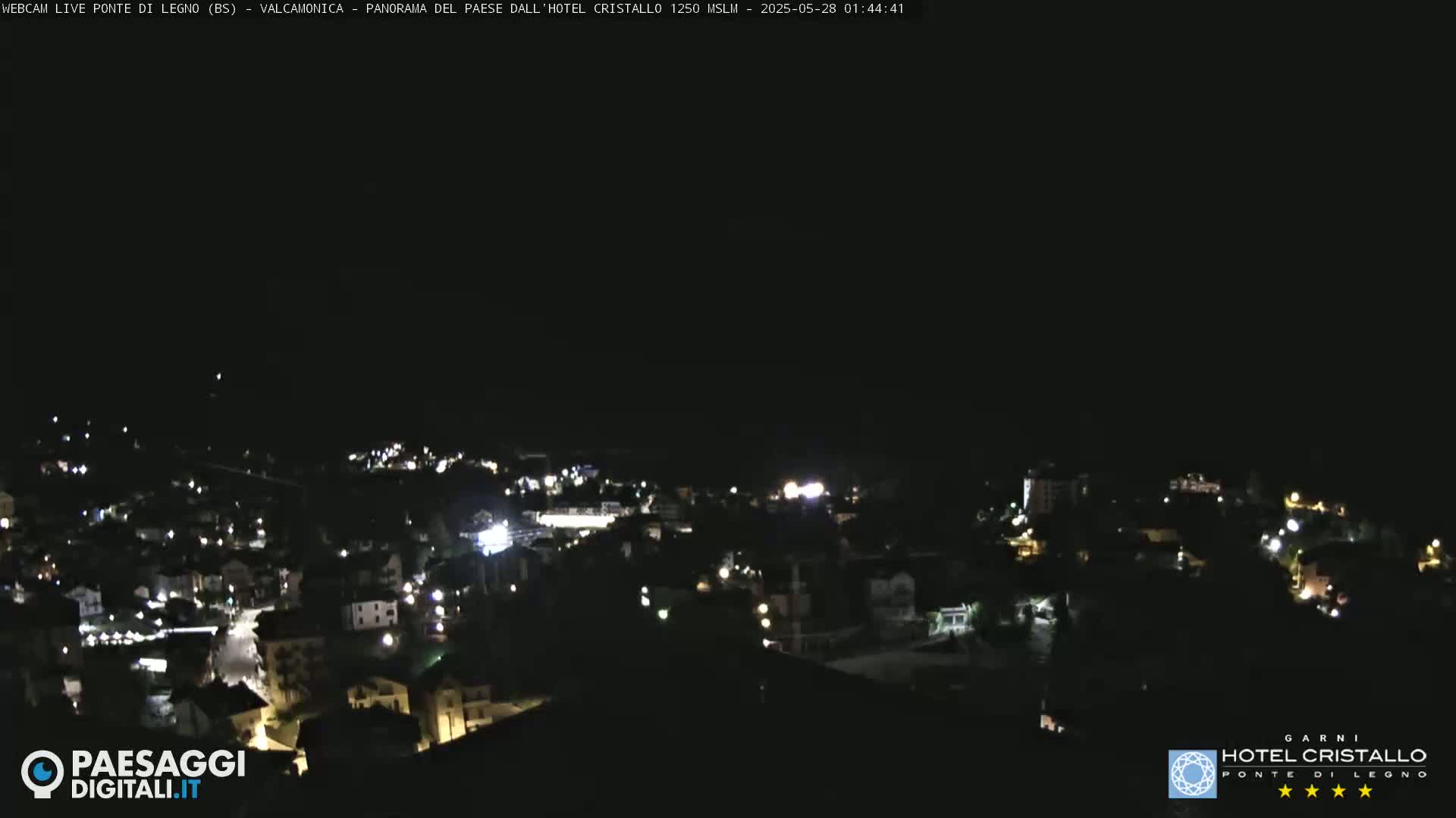 A nighttime, aerial view of a town illuminated by scattered lights under a dark, clear sky.