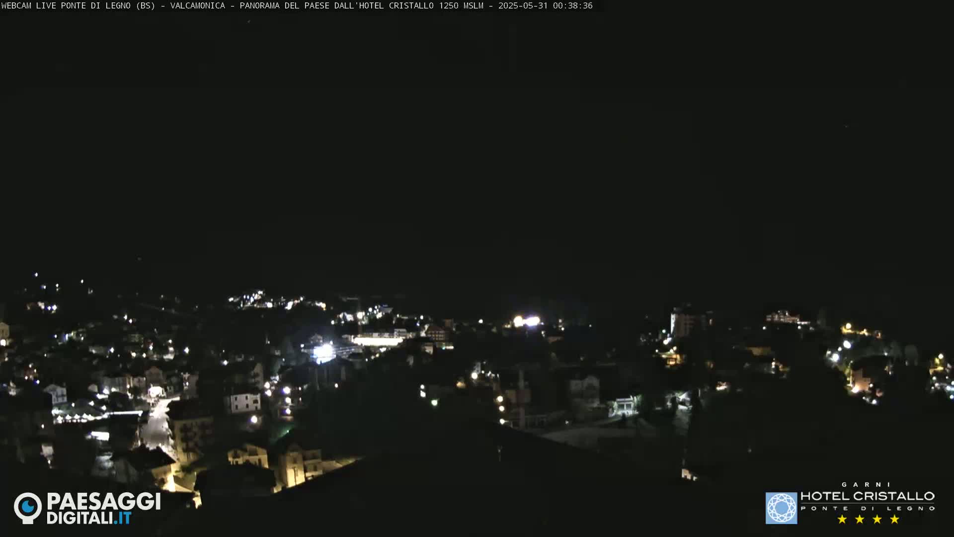 A nighttime, high-angle view of a small town illuminated by scattered lights under a dark sky.