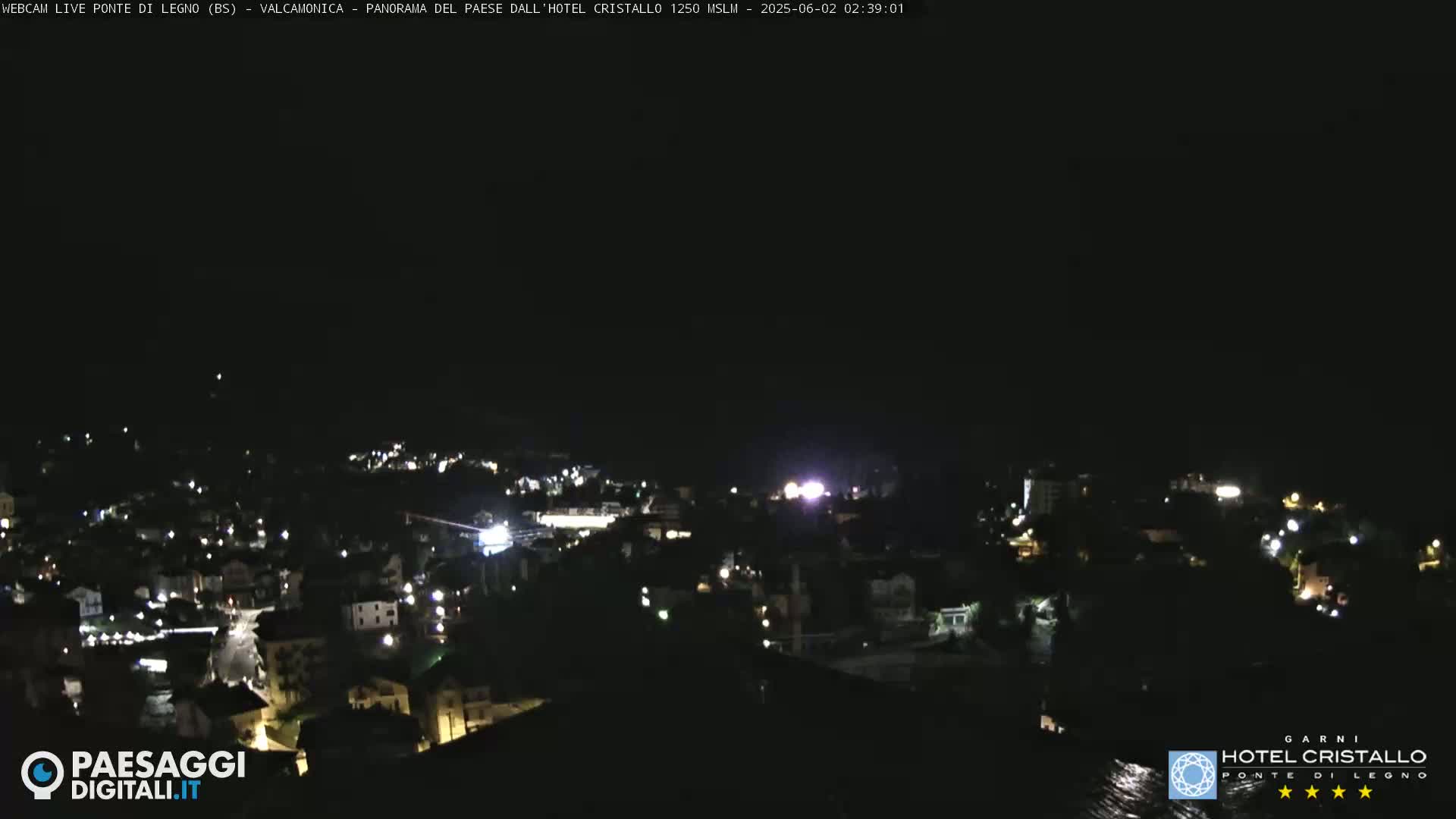 A nighttime, aerial view of a town illuminated by scattered lights under a dark sky.