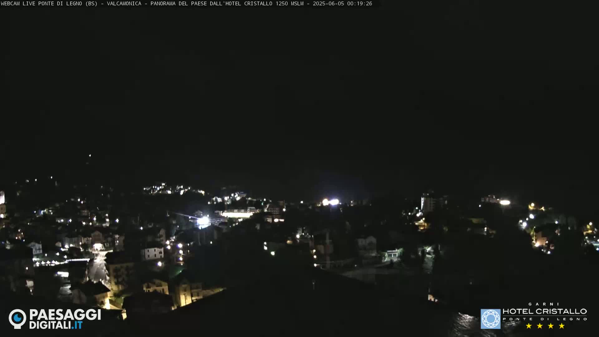 A nighttime view of a town with scattered lights, under a clear, dark sky.