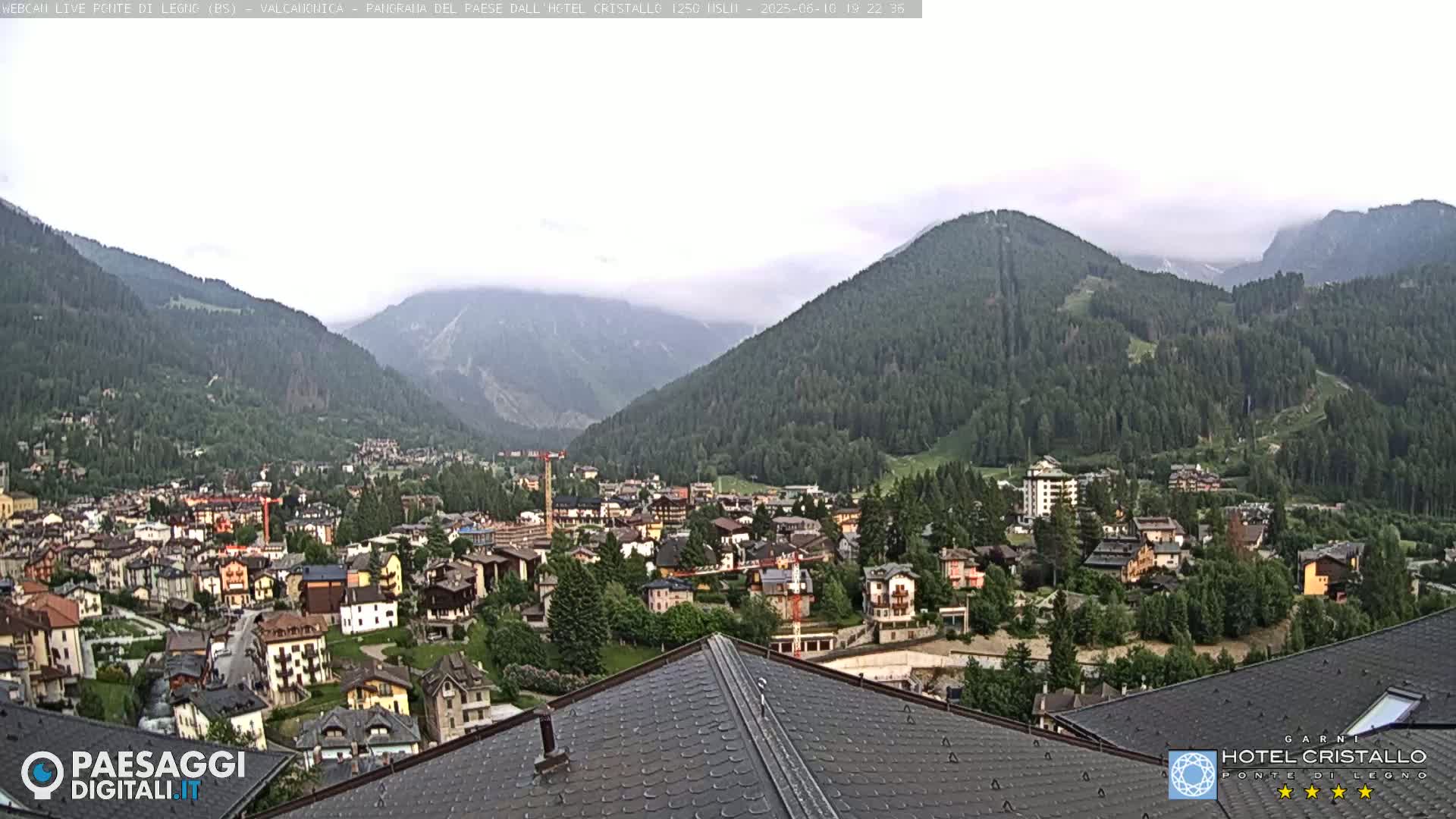 A mountain town nestled in a valley between forested hills on a cloudy day.