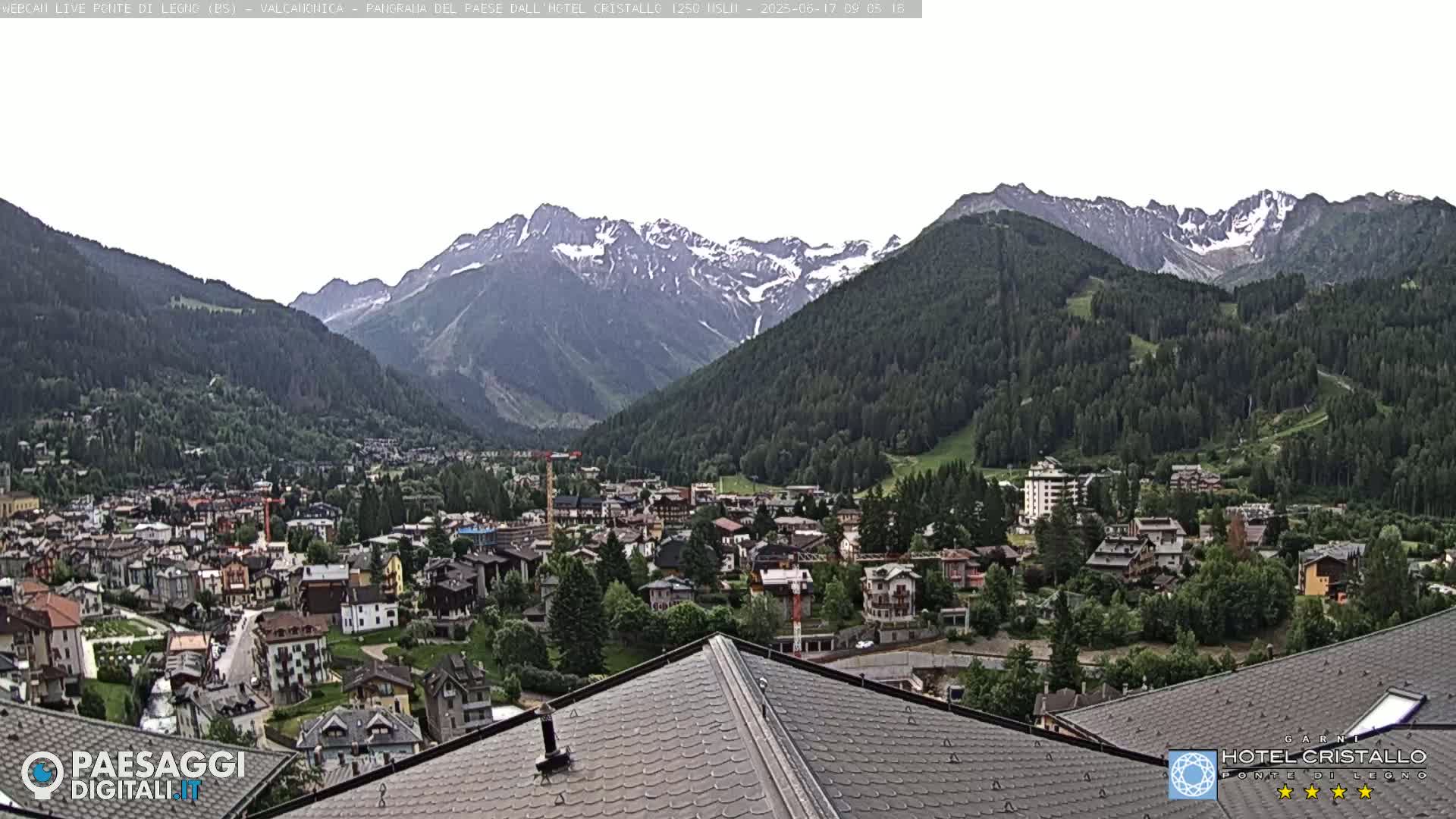 A mountain town nestled in a valley below snow-capped mountains on an overcast day.