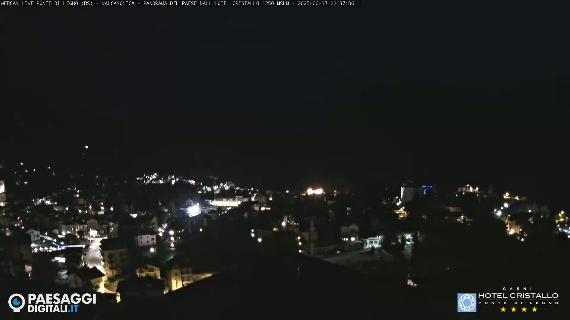 A nighttime view of a town illuminated by scattered lights under a clear, dark sky.