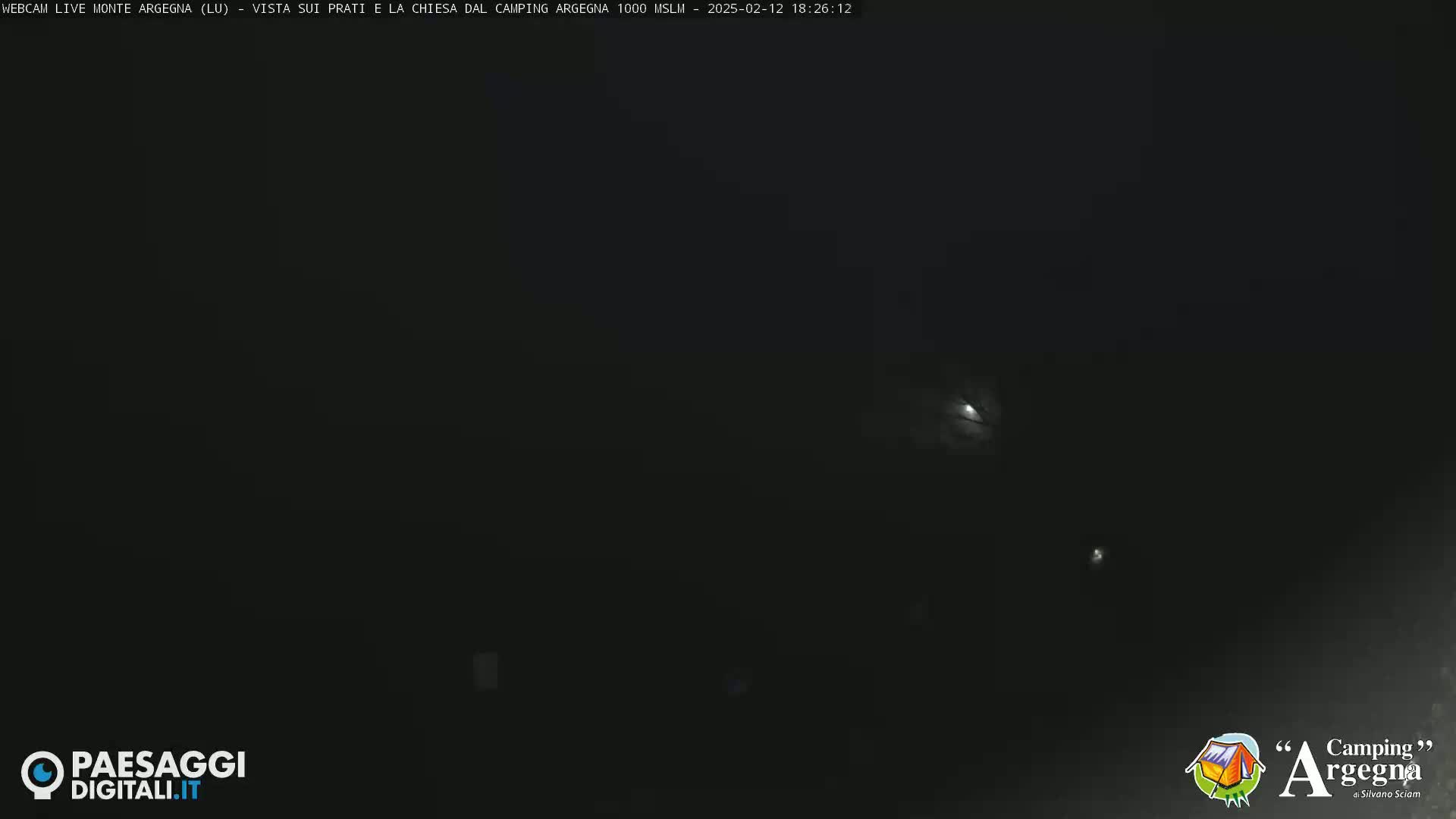 A dark nighttime scene is shown, with a faint light source visible in the distance.