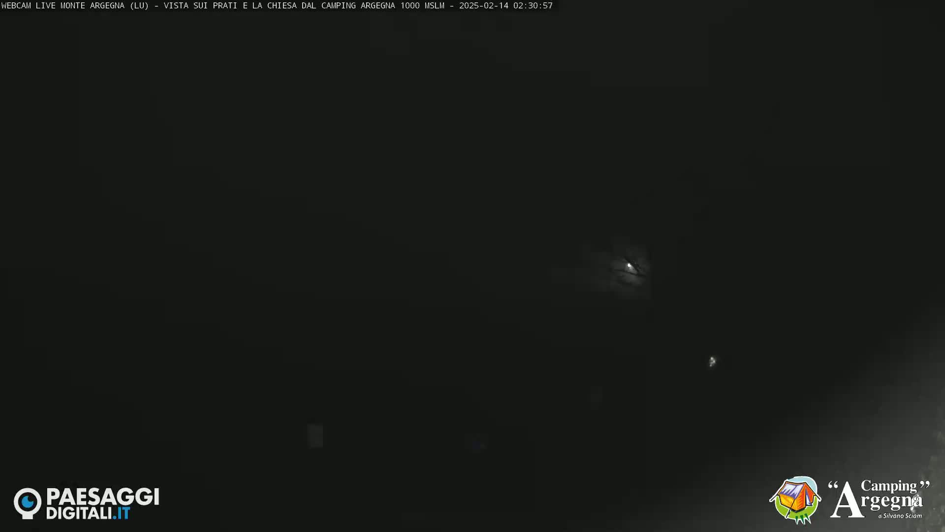 A nighttime, dark outdoor scene shows a sliver of moon visible through a mostly overcast sky.