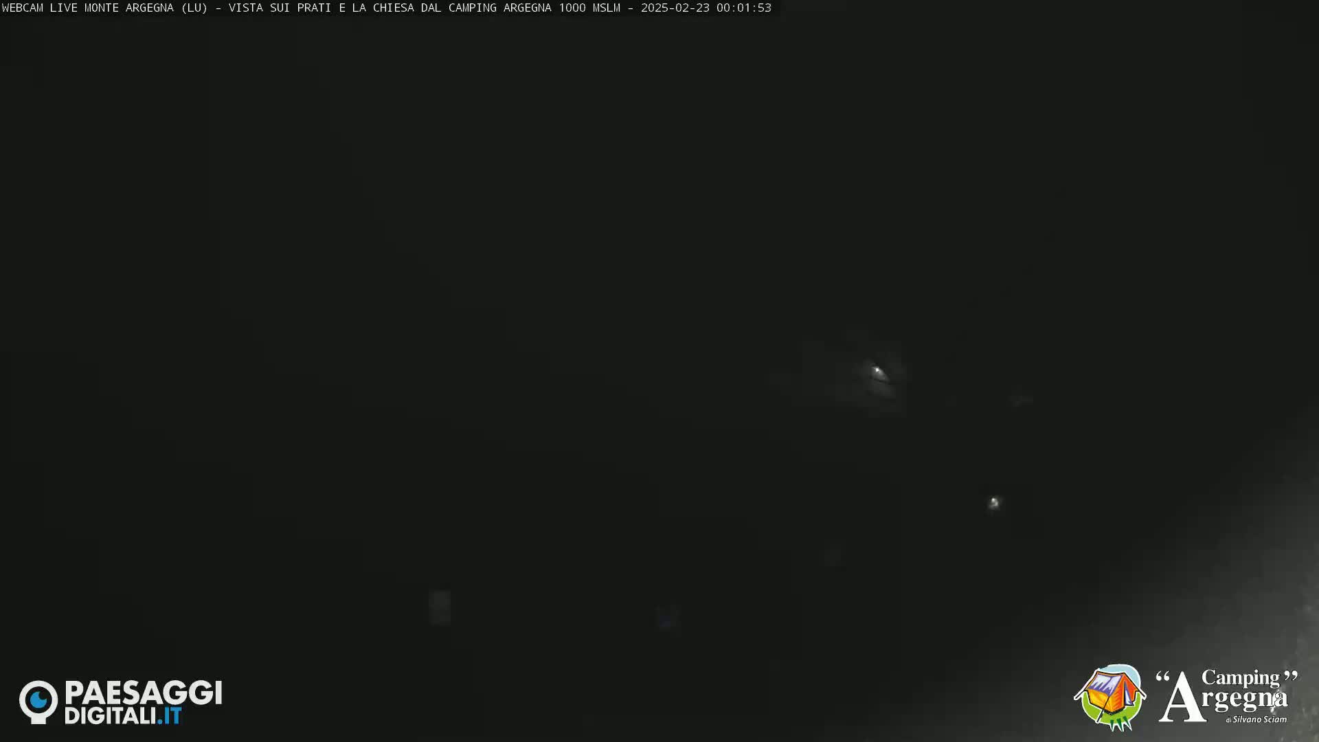 A very dark nighttime scene shows a few distant, faint lights.