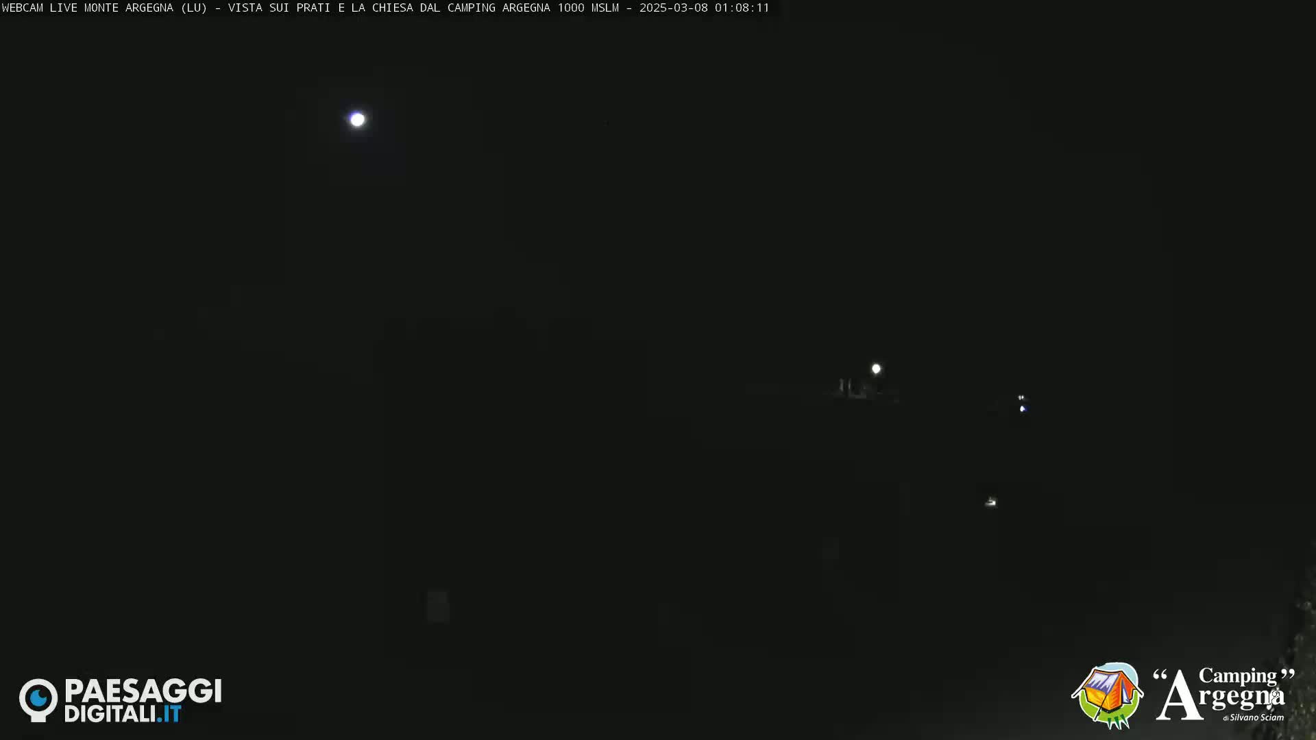 A nighttime outdoor scene shows a moon and distant lights under a clear, dark sky.