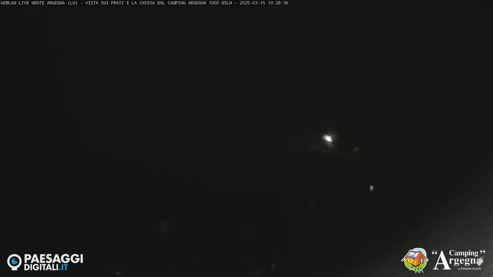 A mostly clear night sky shows a bright moon partially obscured by clouds.