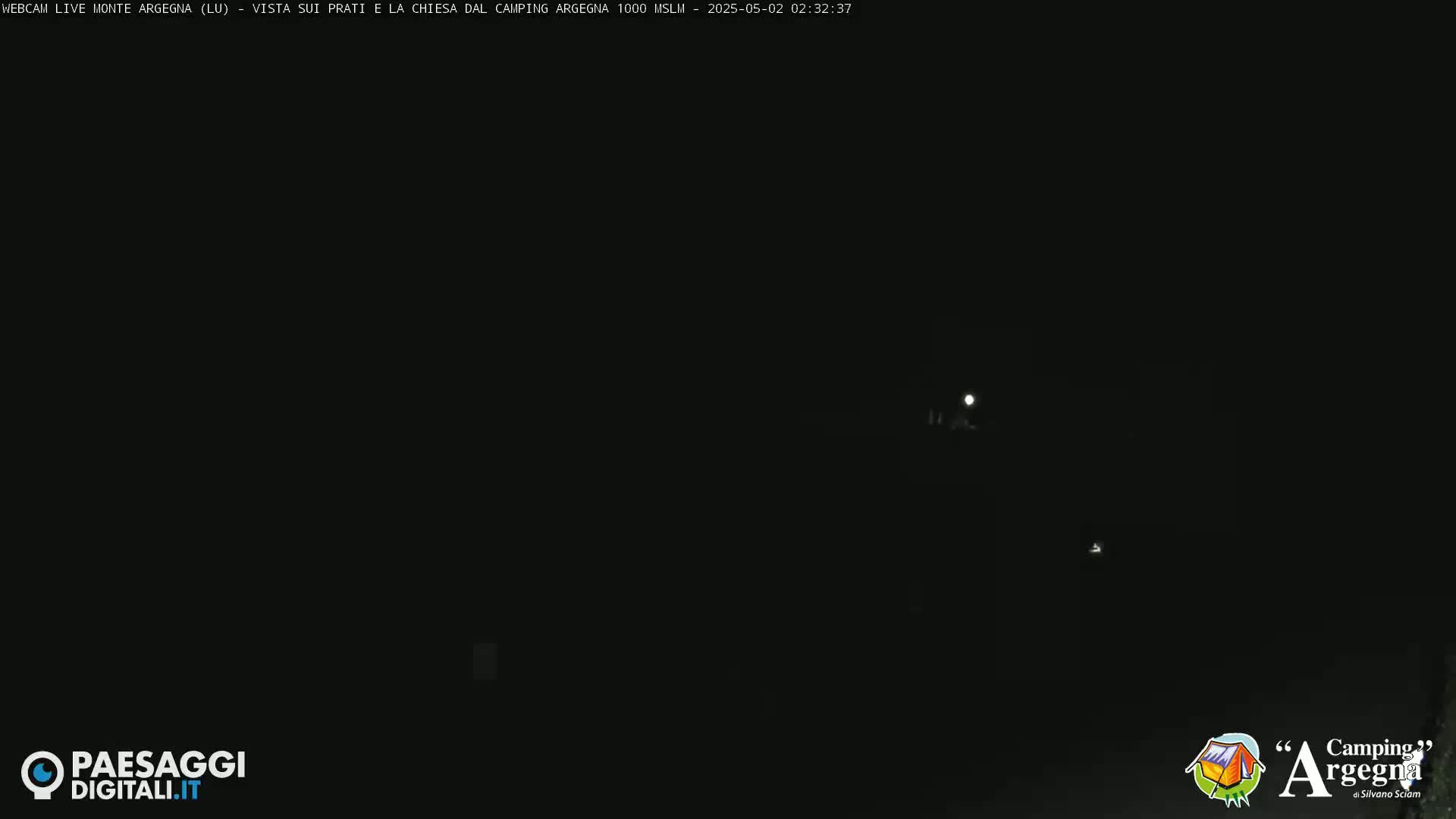 A dark, nighttime scene shows faintly lit features in the distance under a mostly clear sky.