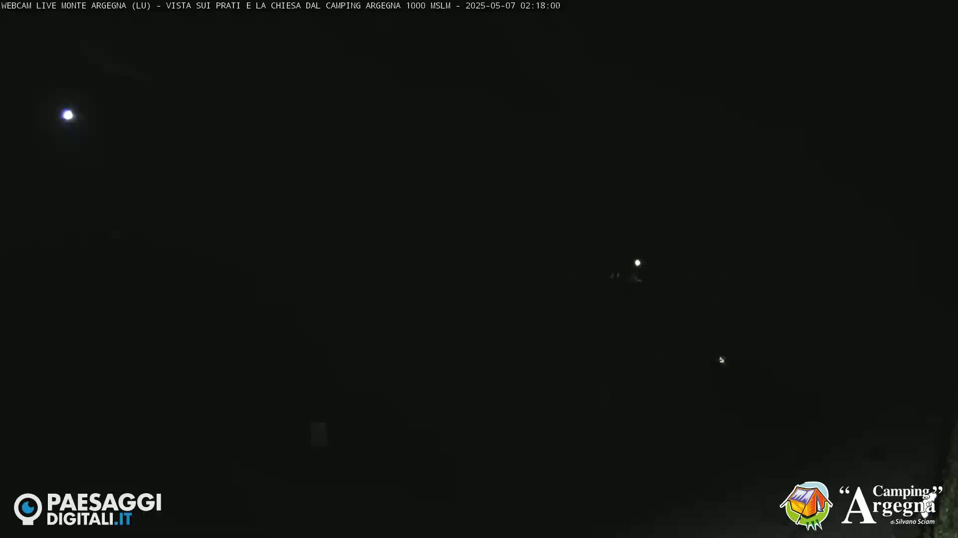 A dark night scene shows a few distant lights and a bright moon.