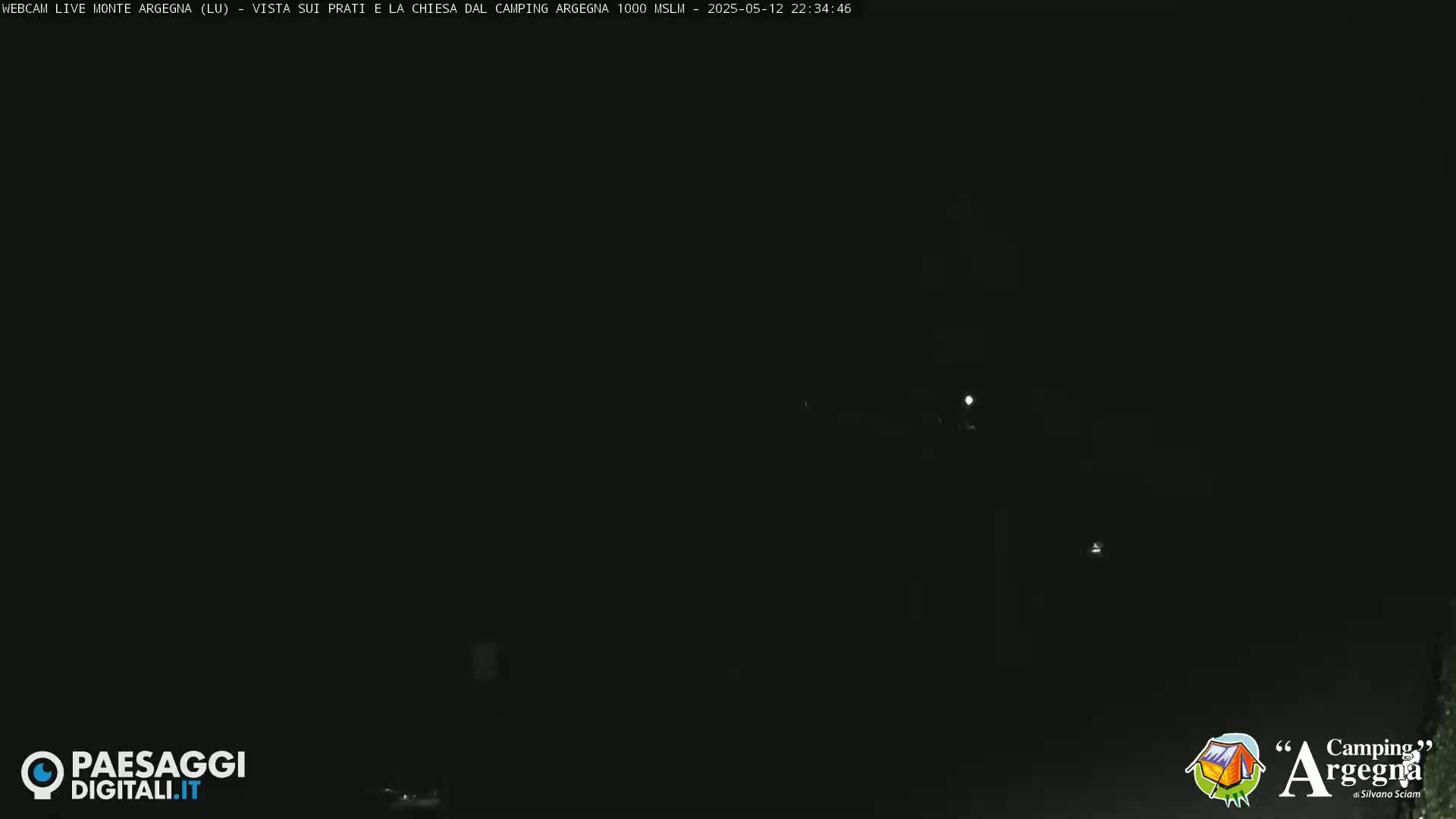 A dark nighttime scene shows a few distant lights in the blackness.