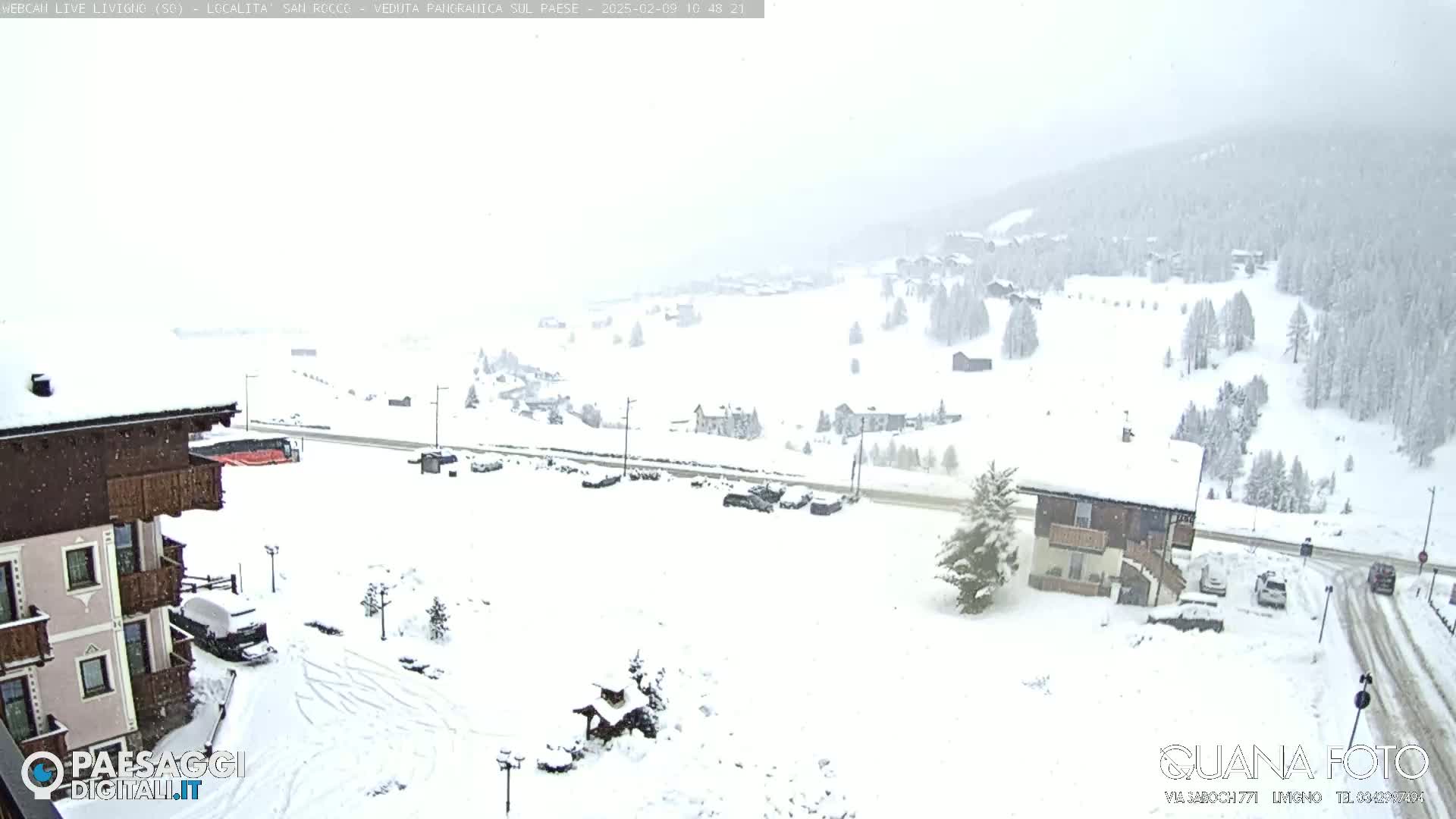 A snow-covered village in a mountainous area is seen during a snowfall.