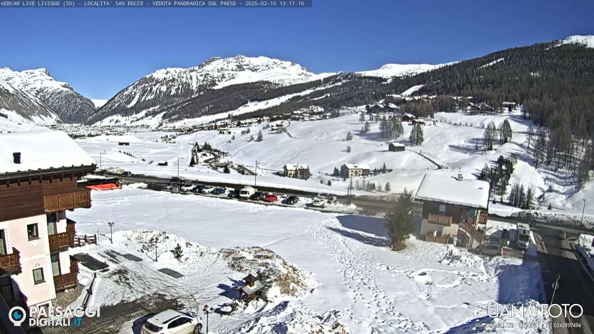 A snow-covered mountain village is viewed from a high vantage point on a sunny day.