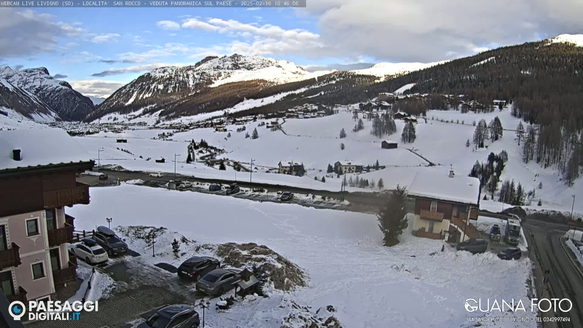 A snow-covered mountain valley village scene, under a mostly clear sky.