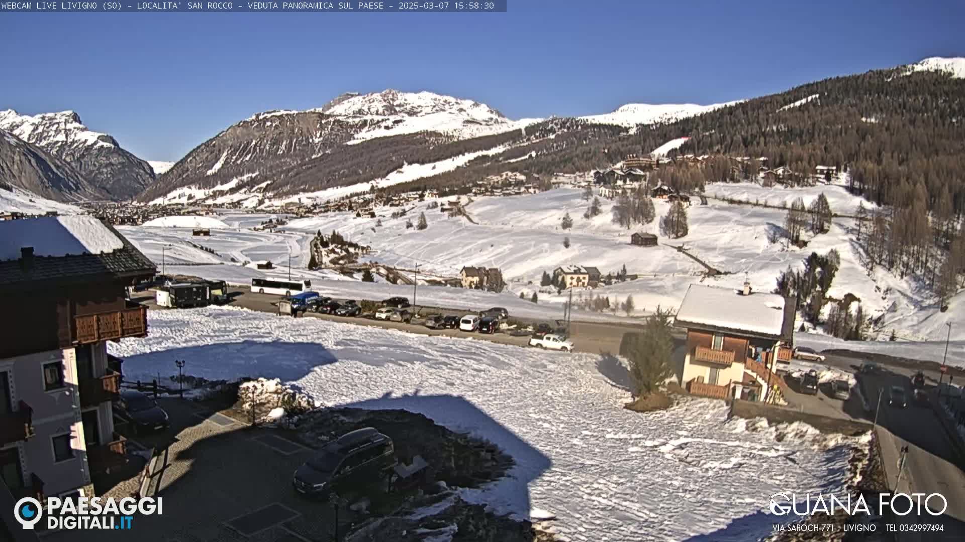 A snow-covered mountain valley town is viewed from a high vantage point on a sunny day.