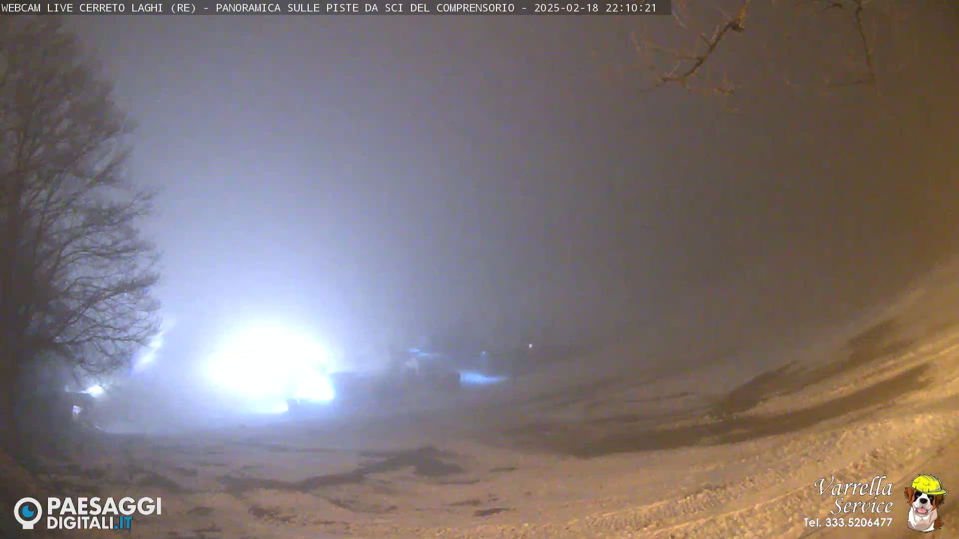 A snow-covered landscape is dimly lit at night under a foggy sky.