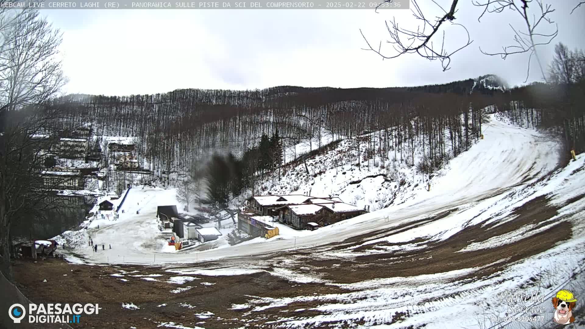 A snow-covered ski slope with several buildings and sparsely populated snowy terrain, under an overcast sky.