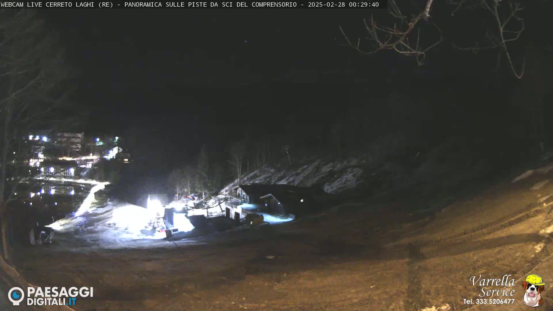 A nighttime view of a snow-covered ski resort with illuminated buildings and slopes.
