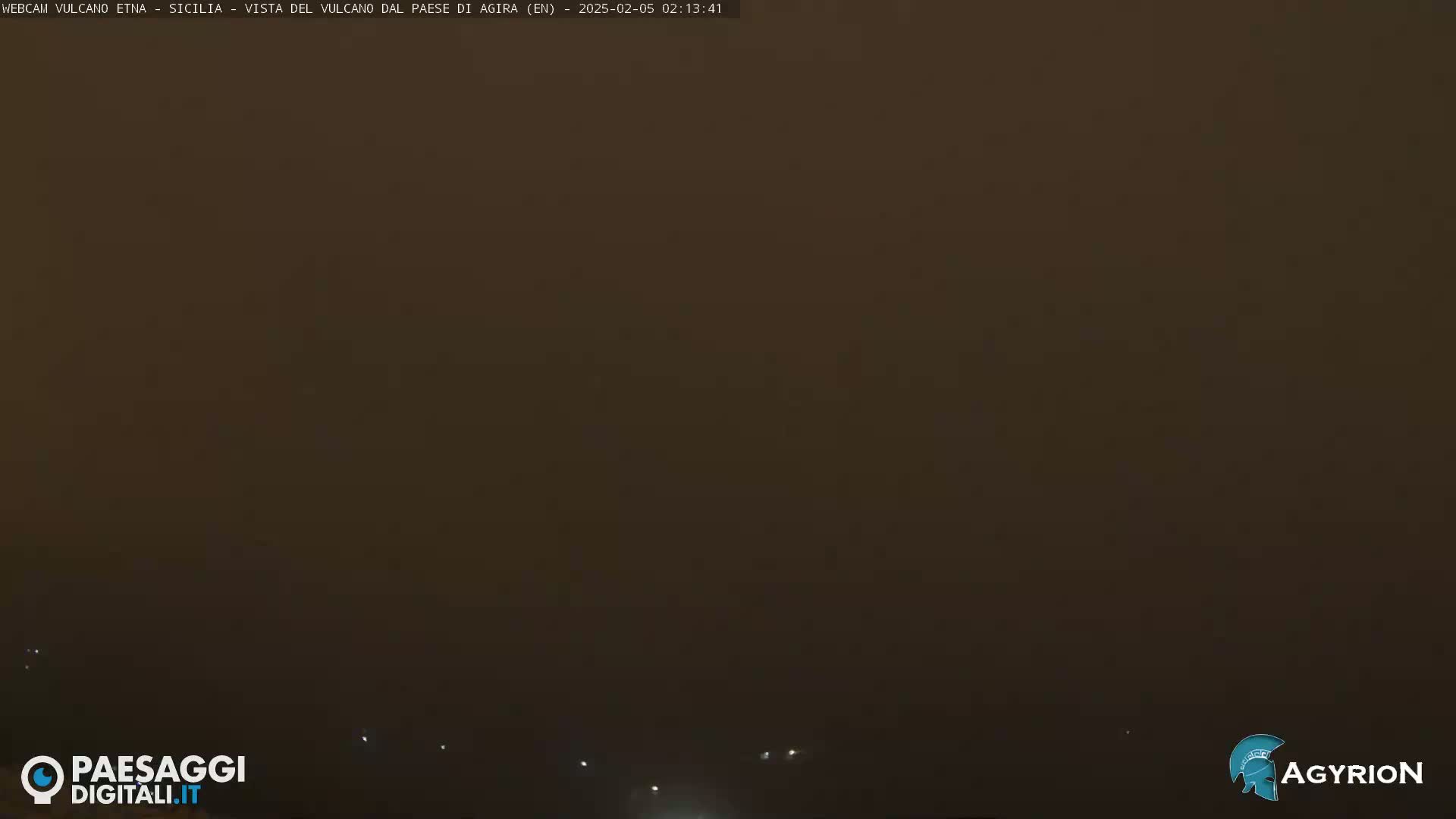 A hazy, dark brown landscape is visible at night, with a few faint lights in the distance.